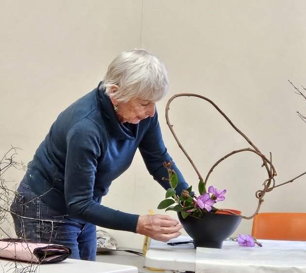 Sandi arranging twisted vine with tibouchina, lasiandra in an open pottery container