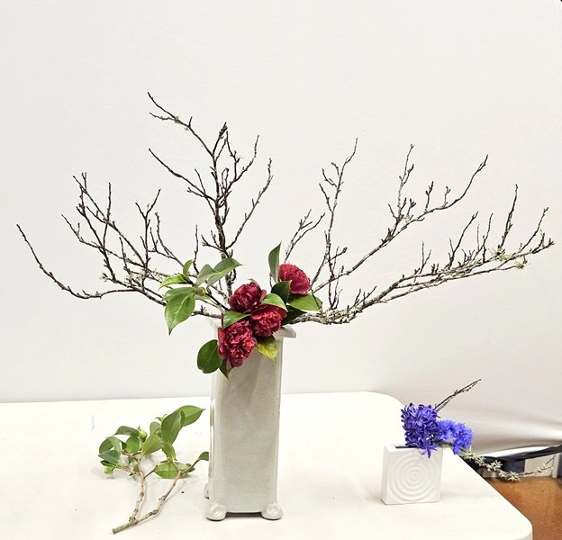 Lyn arranged bare branches with camellia flowers and leaves in a tall porcelain vase
