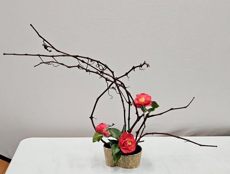 In a low pottery container, Yoko arranged grape vines with camellia flowers and leaves