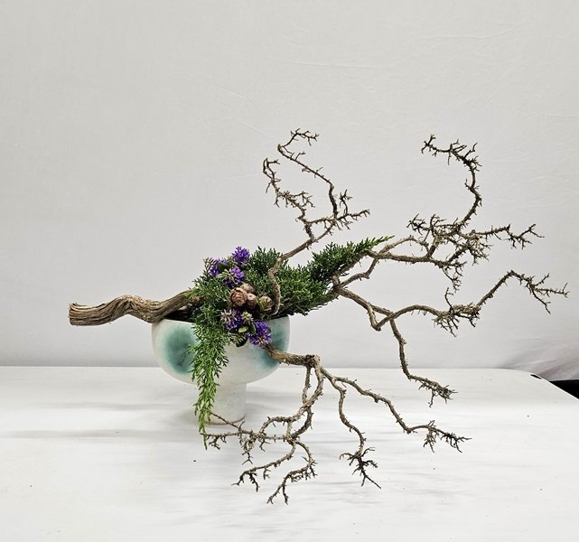 Anna used a thick, bare branch of rosemary with purple flowers and conifer leaves and cones in an interesting container