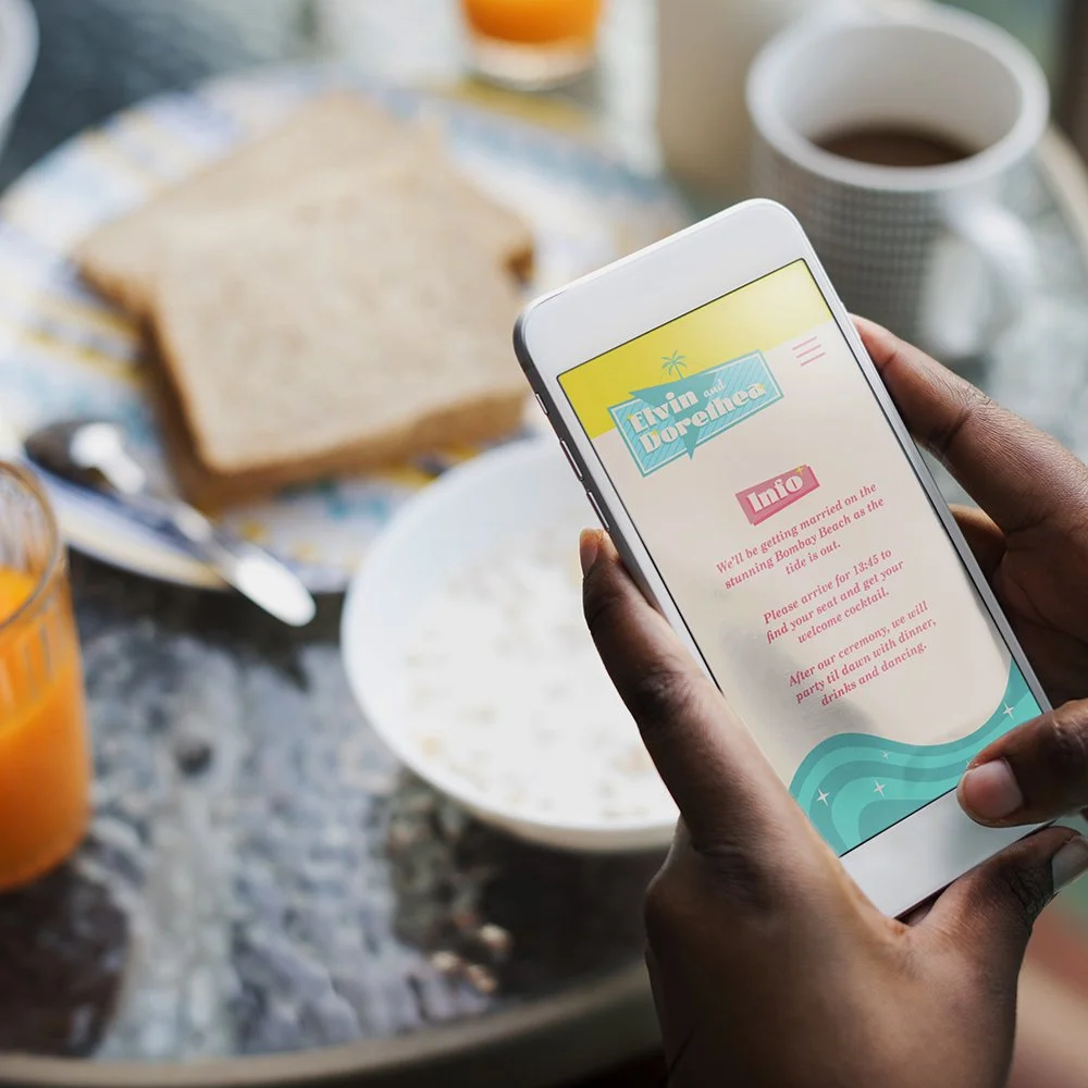 Black hands hold a mobile phone displaying a wedding website, and in the background is a cafe scene.
