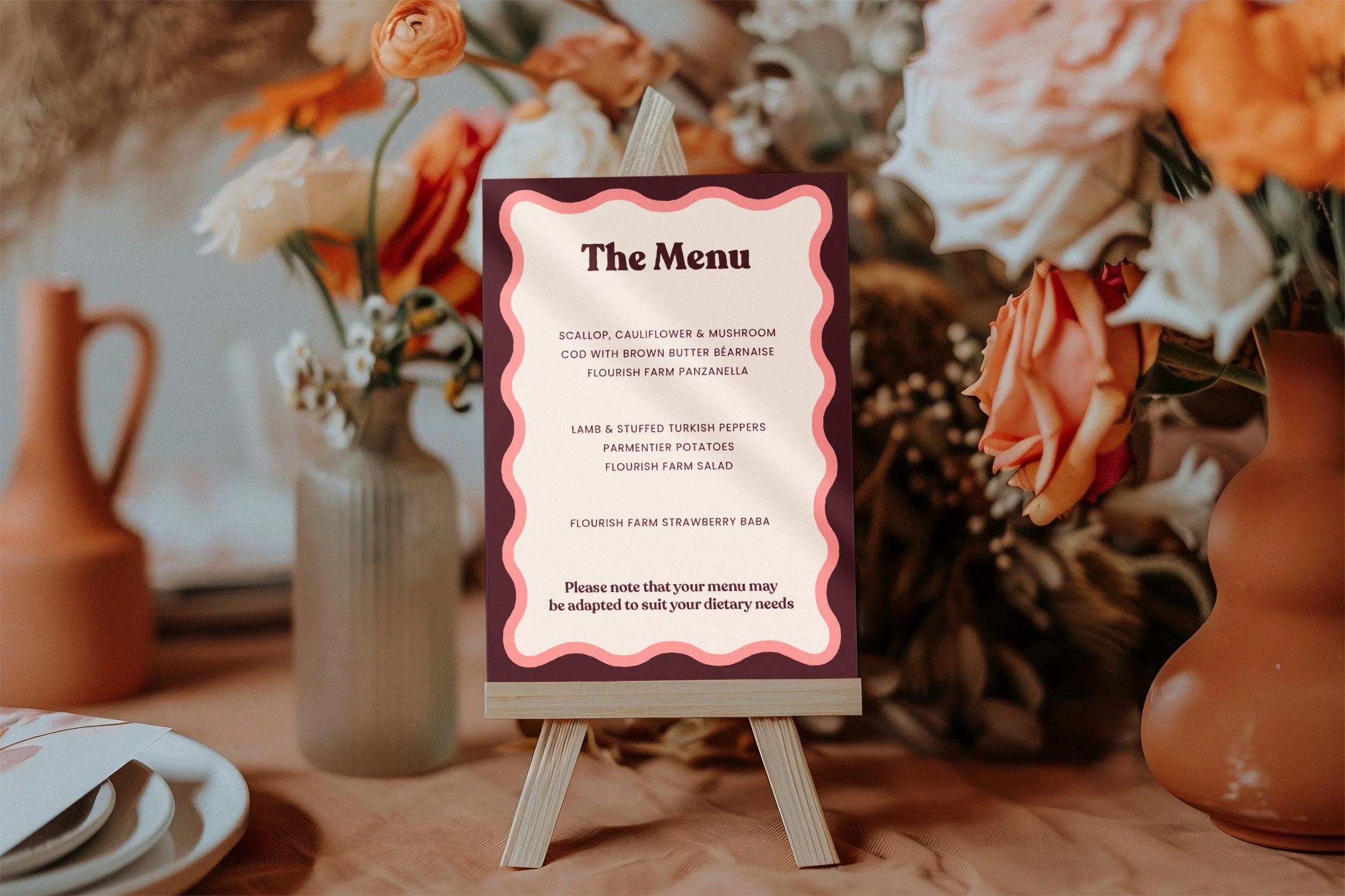 A wedding table with vases of flowers, plates and a menu on a mini easel.