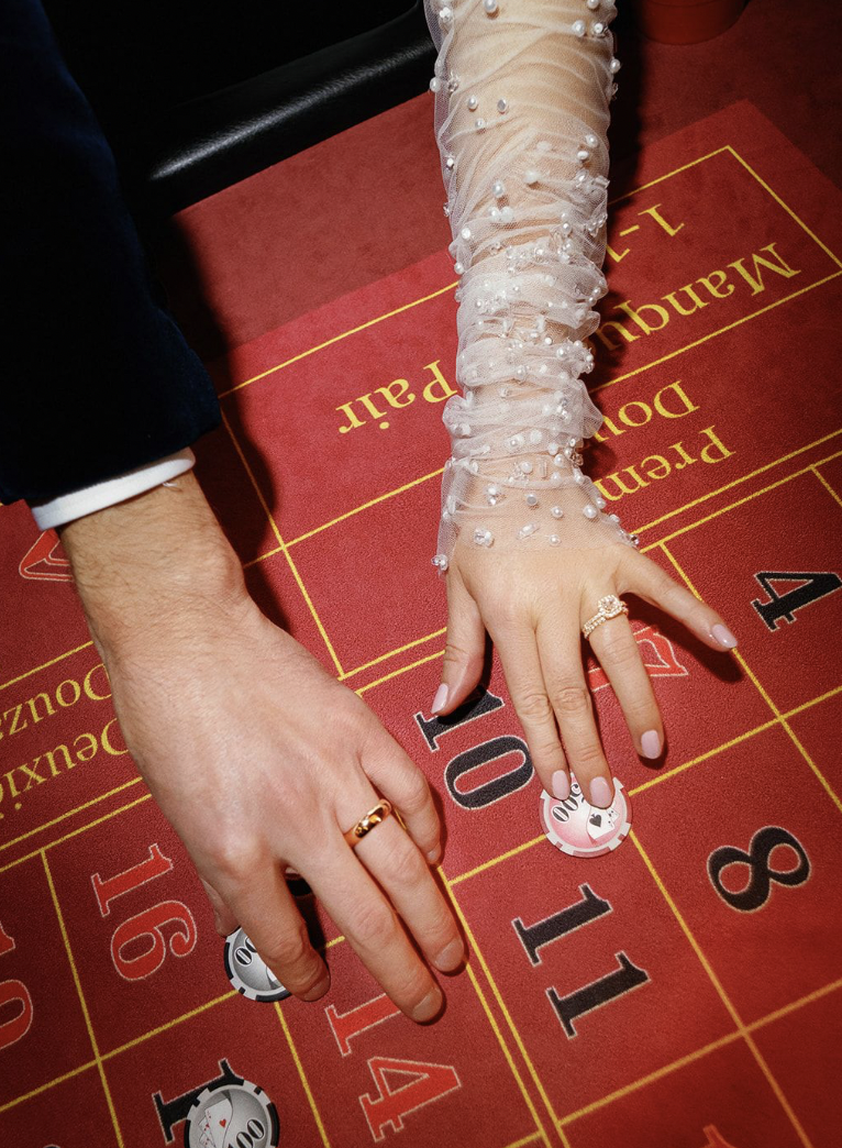 The arms of two newlyweds can be see on a gambling table with chips.