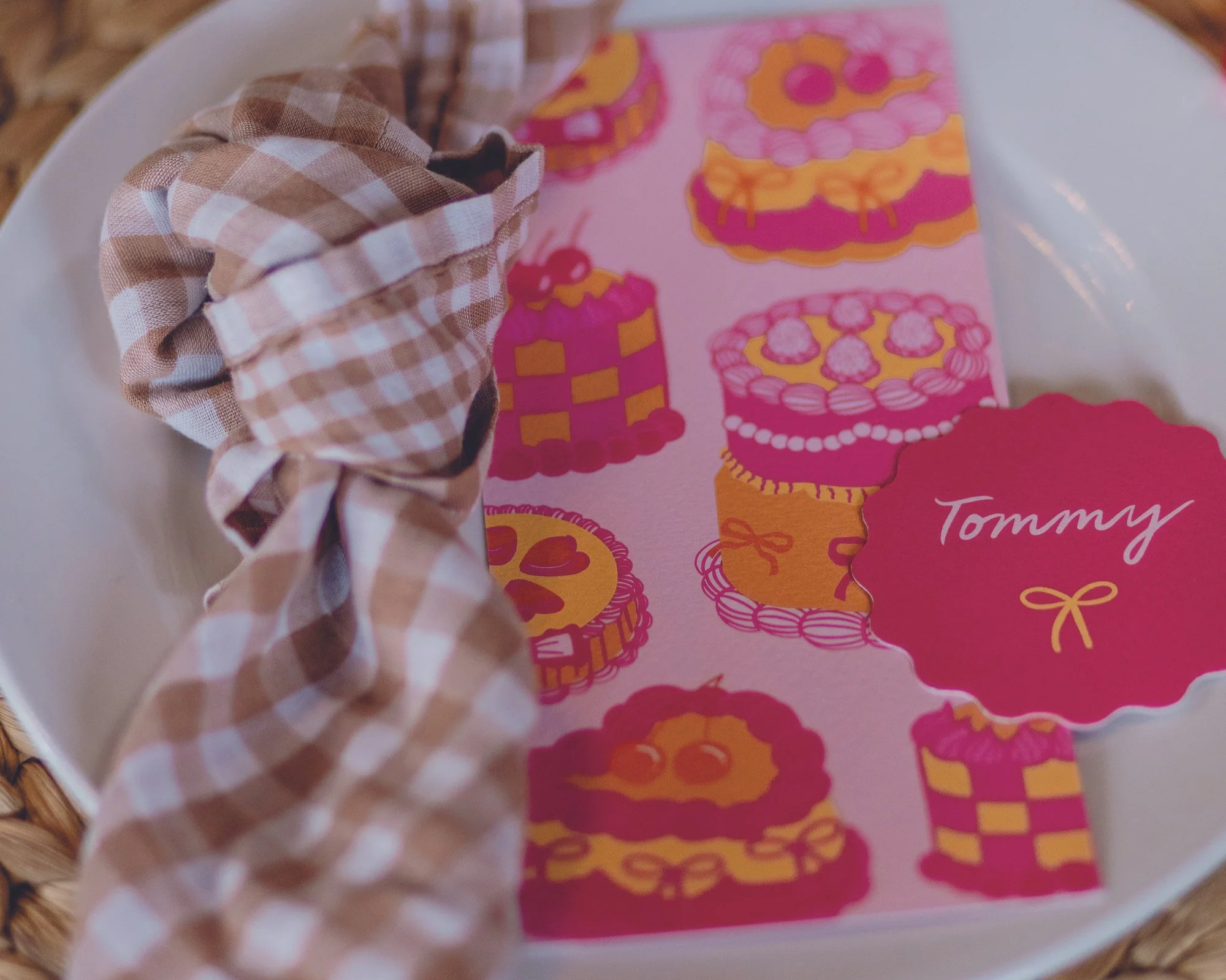 A pink menu and wavy circle pink place card with a knotted gingham napkin.