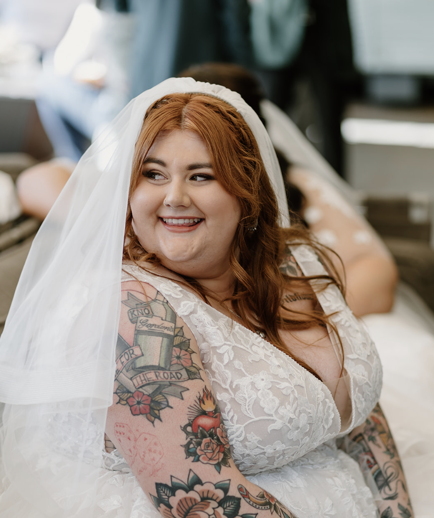 A bride with ginger red hair smiles over her right shoulder.