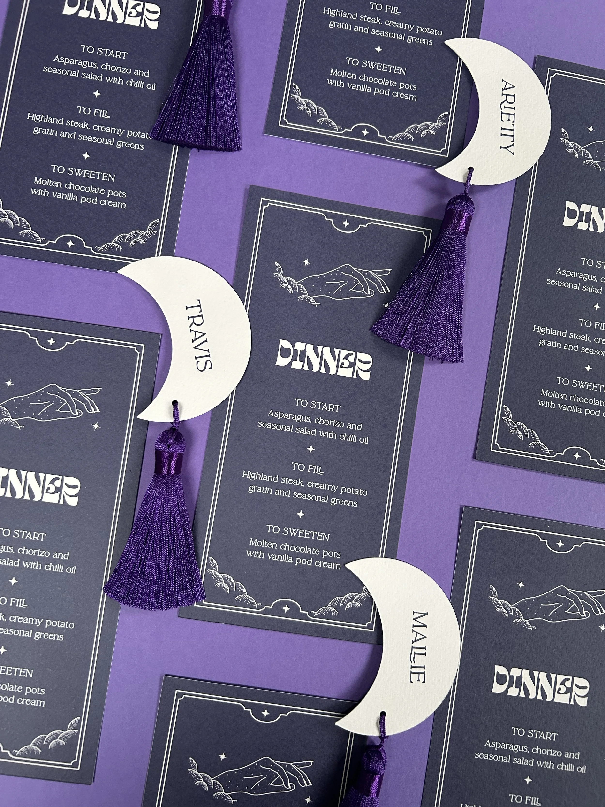 Dark long menus with moon-shaped tasselled placecards.