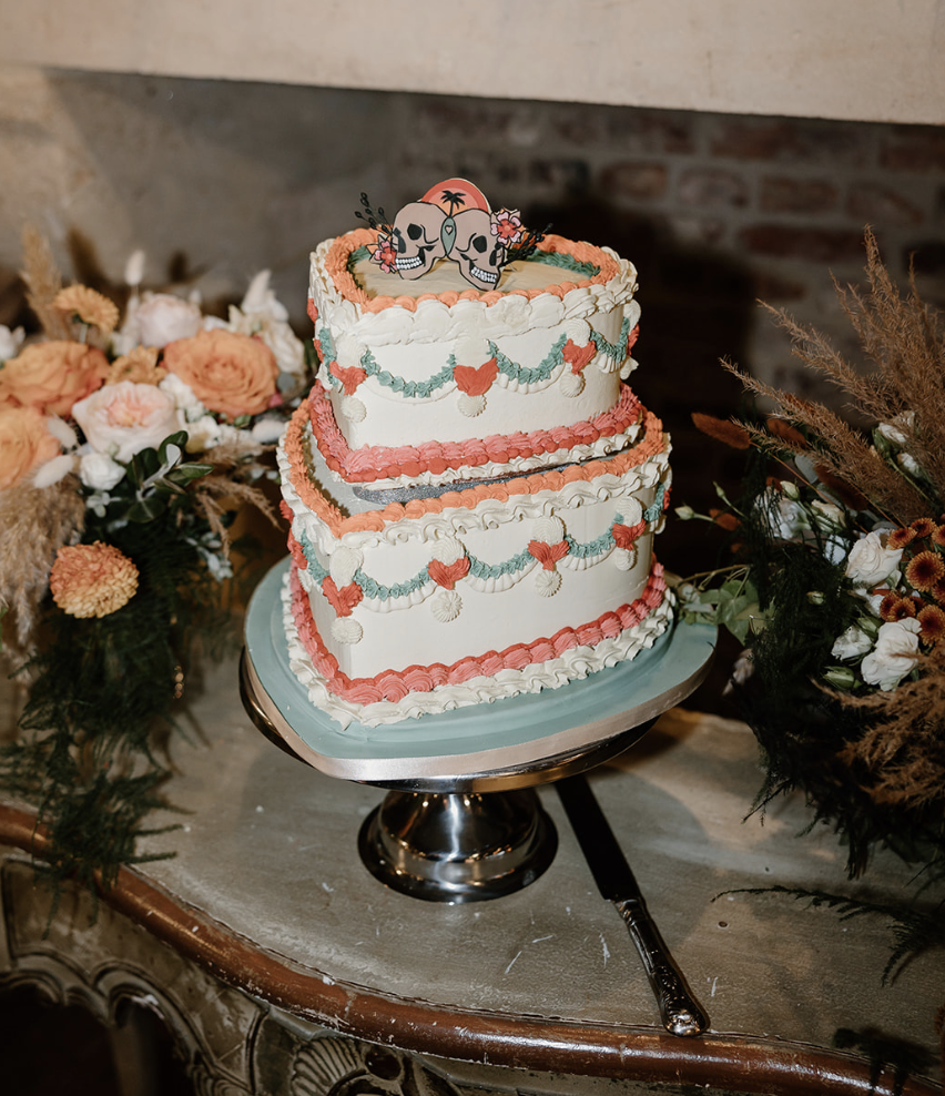 A frilly iced tiered cake topped with a motif of two skulls.