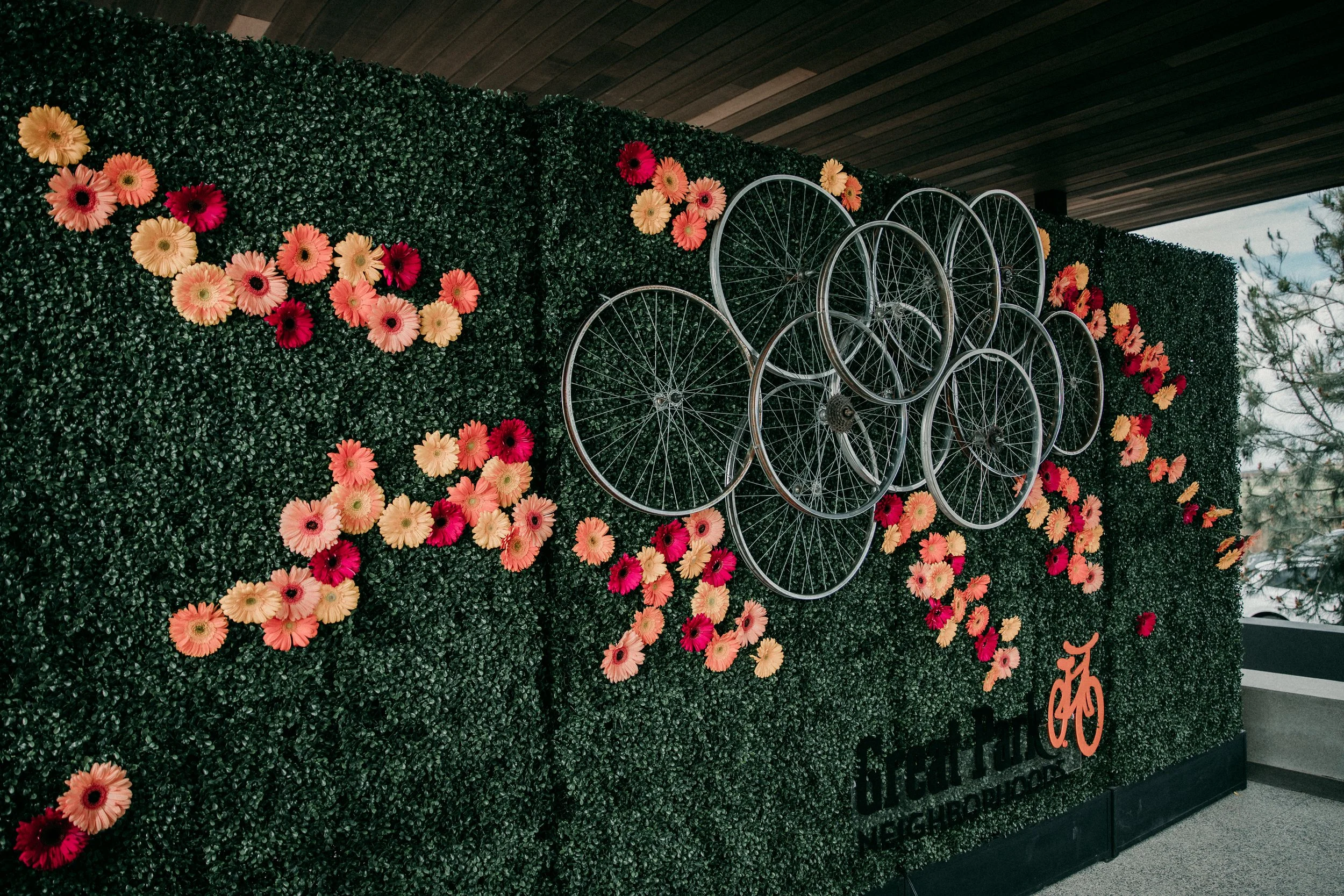 Custom floral backdrop featuring pink, orange and red florwers with decorative vintage bicycles, creating a colorful focal point for a Model Grand Opening Corporate Event. 