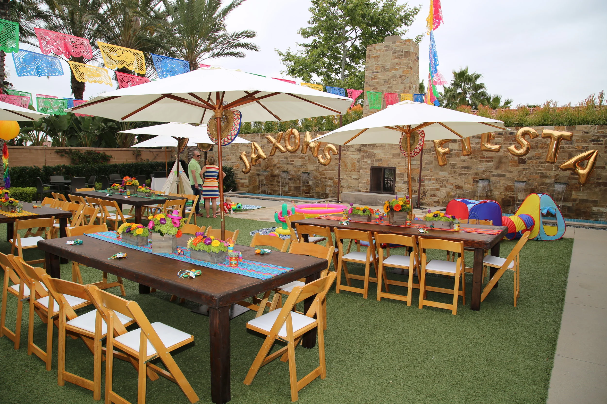 Professionally styled outdoor birthday party with coordinated dining tables, elegant lounge furniture, decorated trees, and coordinated themed styling. 