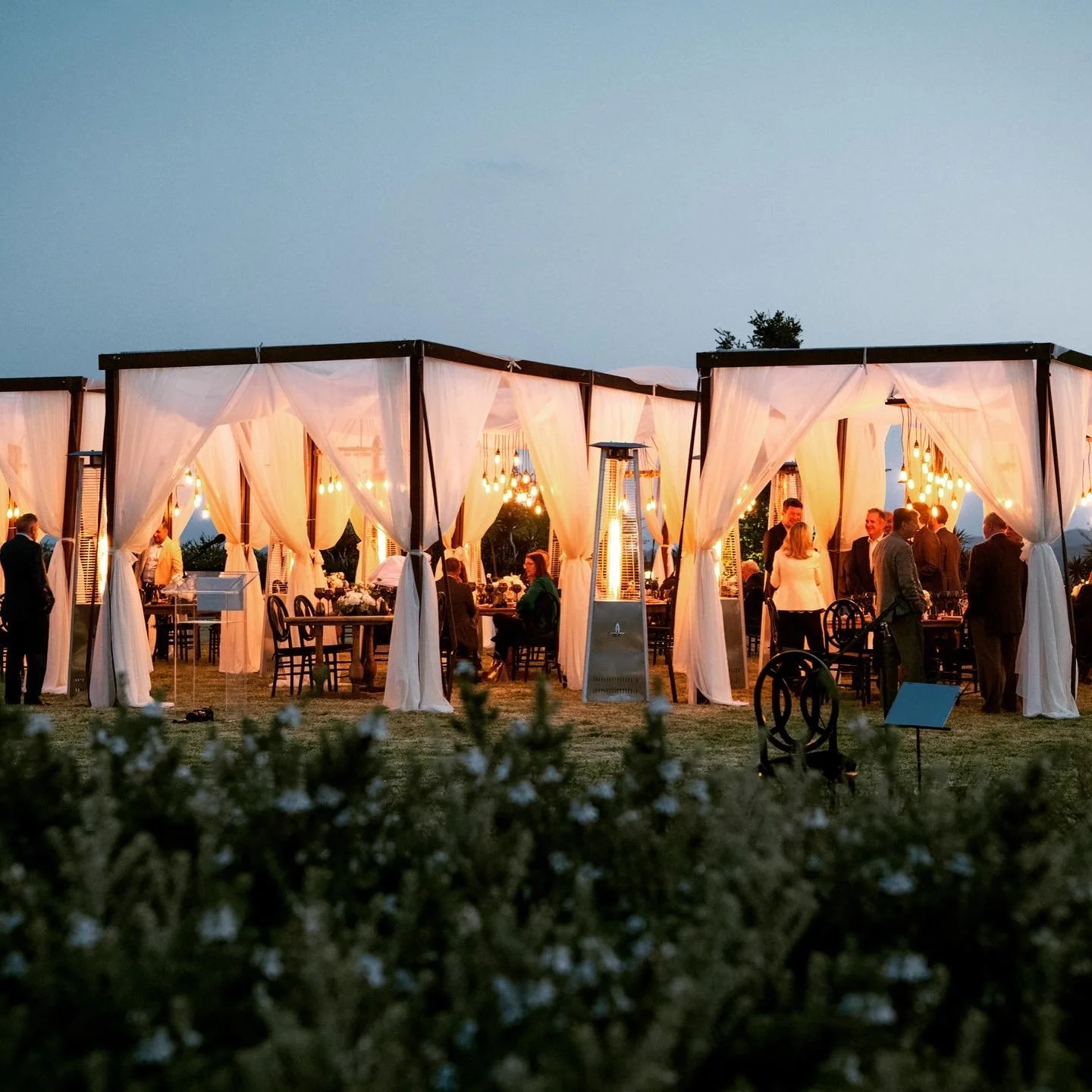 Outdoor corporate event VIP Reception featuring illuminated event structures, elegant lounge seating, and guests gathered beneath the night sky.