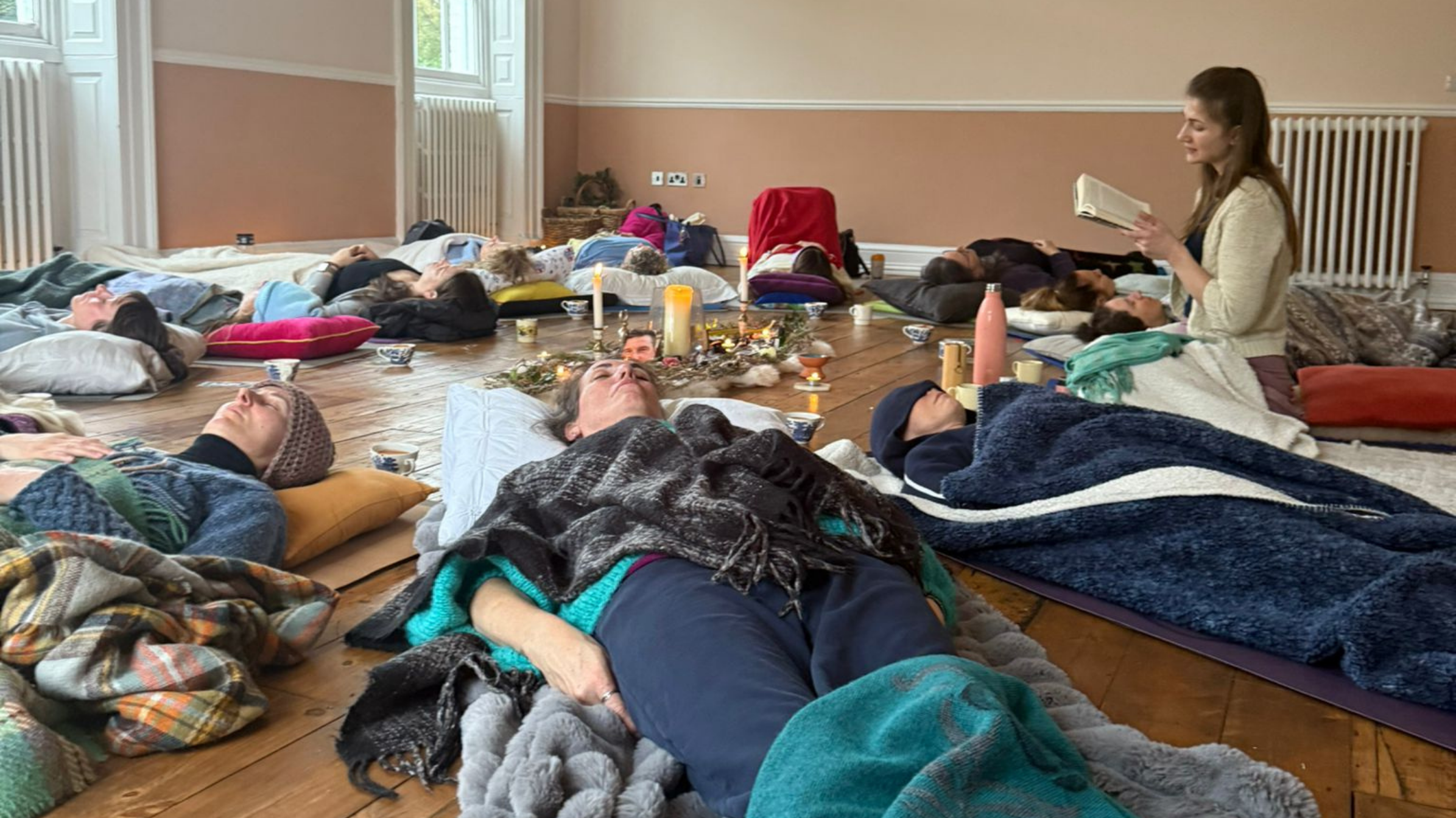 woman laying in a circle with a devotional altar with candles and plant in the middle