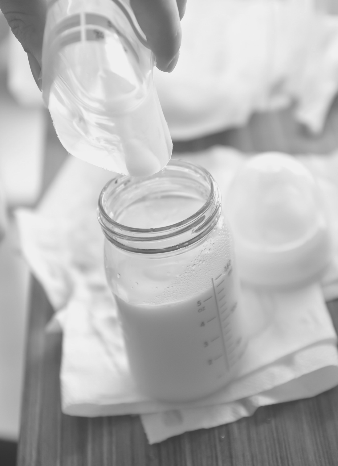 Photo of thawed pumped breast milk being poured into a bottle for feeding.