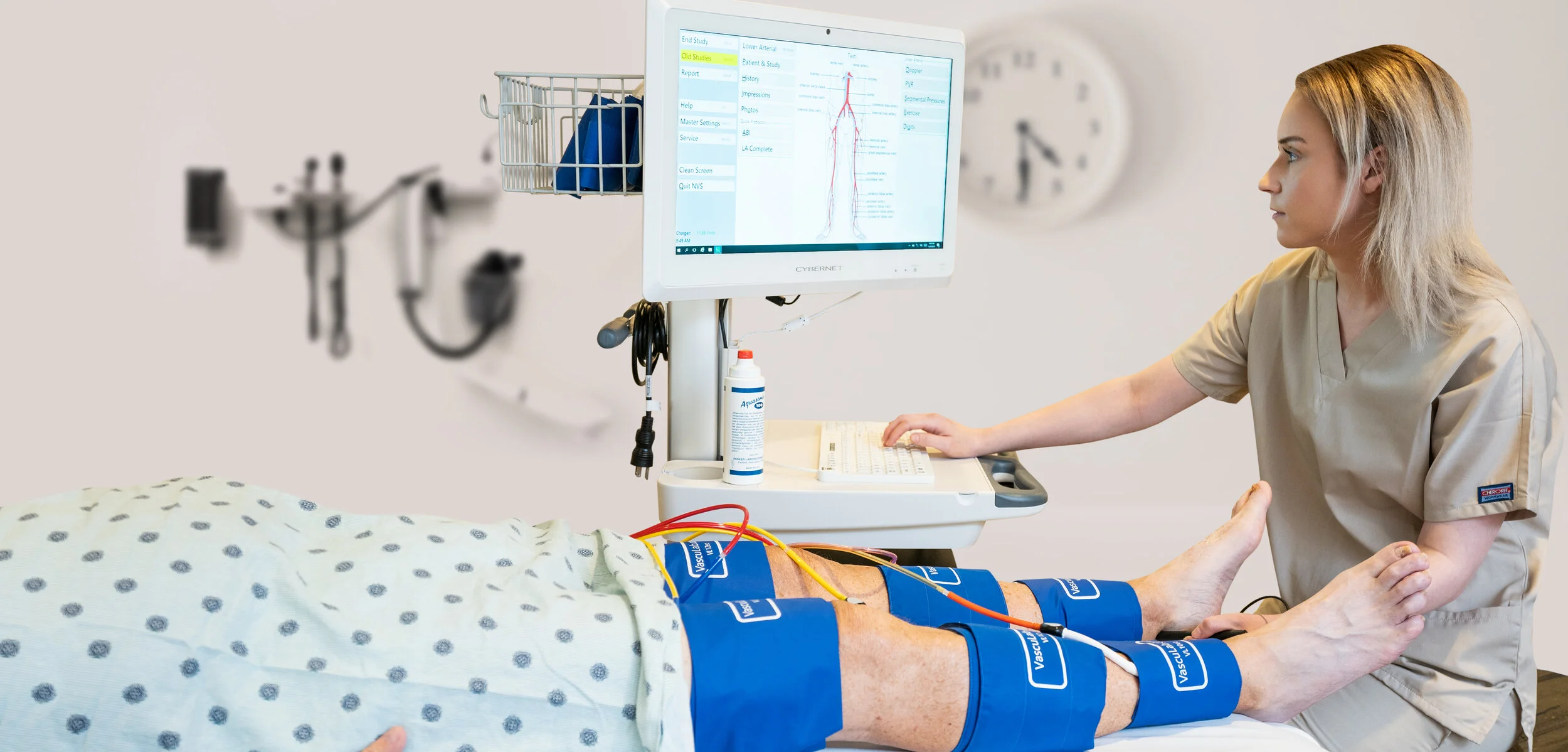 Technician operating the VascuLab next to patient wearing sensors
