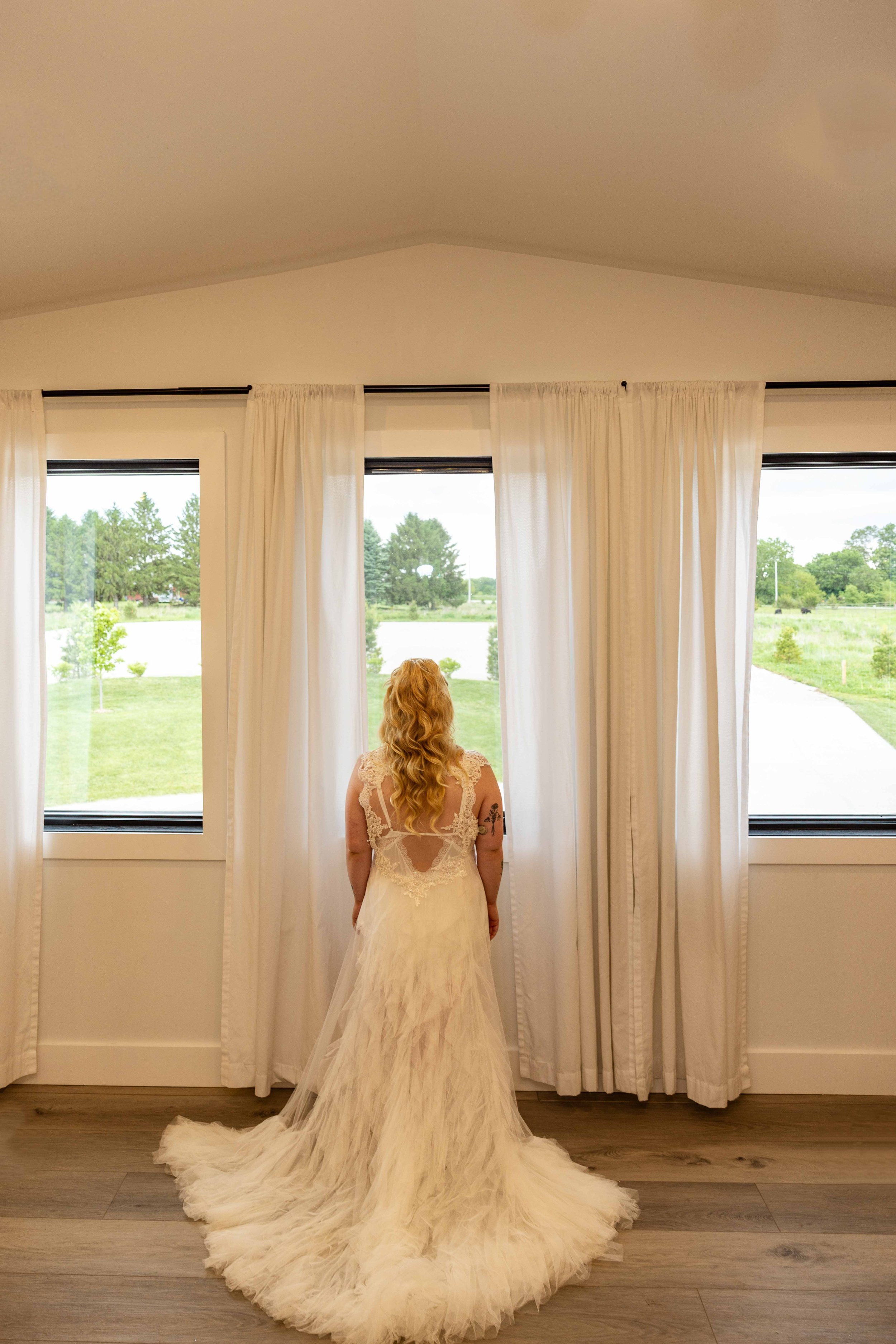 Bride admiring her EMBODY Bridal wedding dress inside Walnut Ridge Venue before the ceremony.