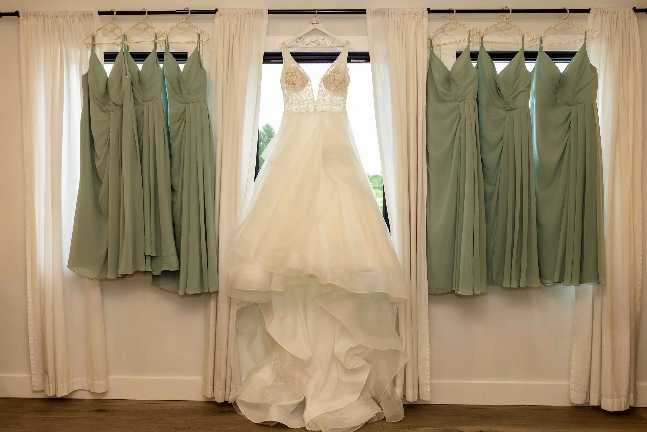 Bride wearing an ENBODY Bridal wedding dress surrounded by bridesmaids in sage green dresses at Walnut Ridge Venue in Iowa.