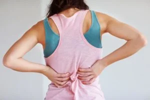 woman in exercise and sports wear with muscle stiffness in back