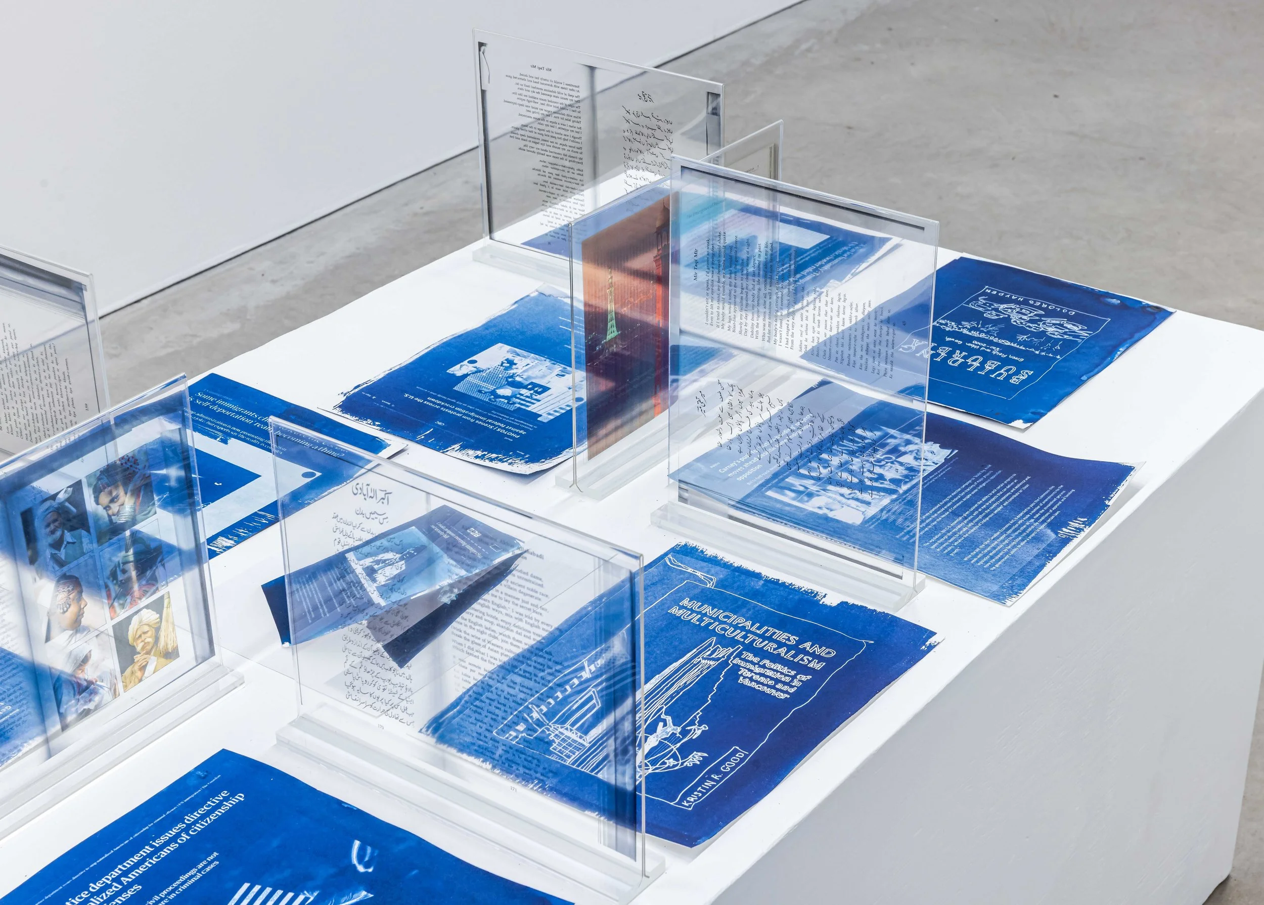 cyanotypes and plexi frames with book page scanson a white box
