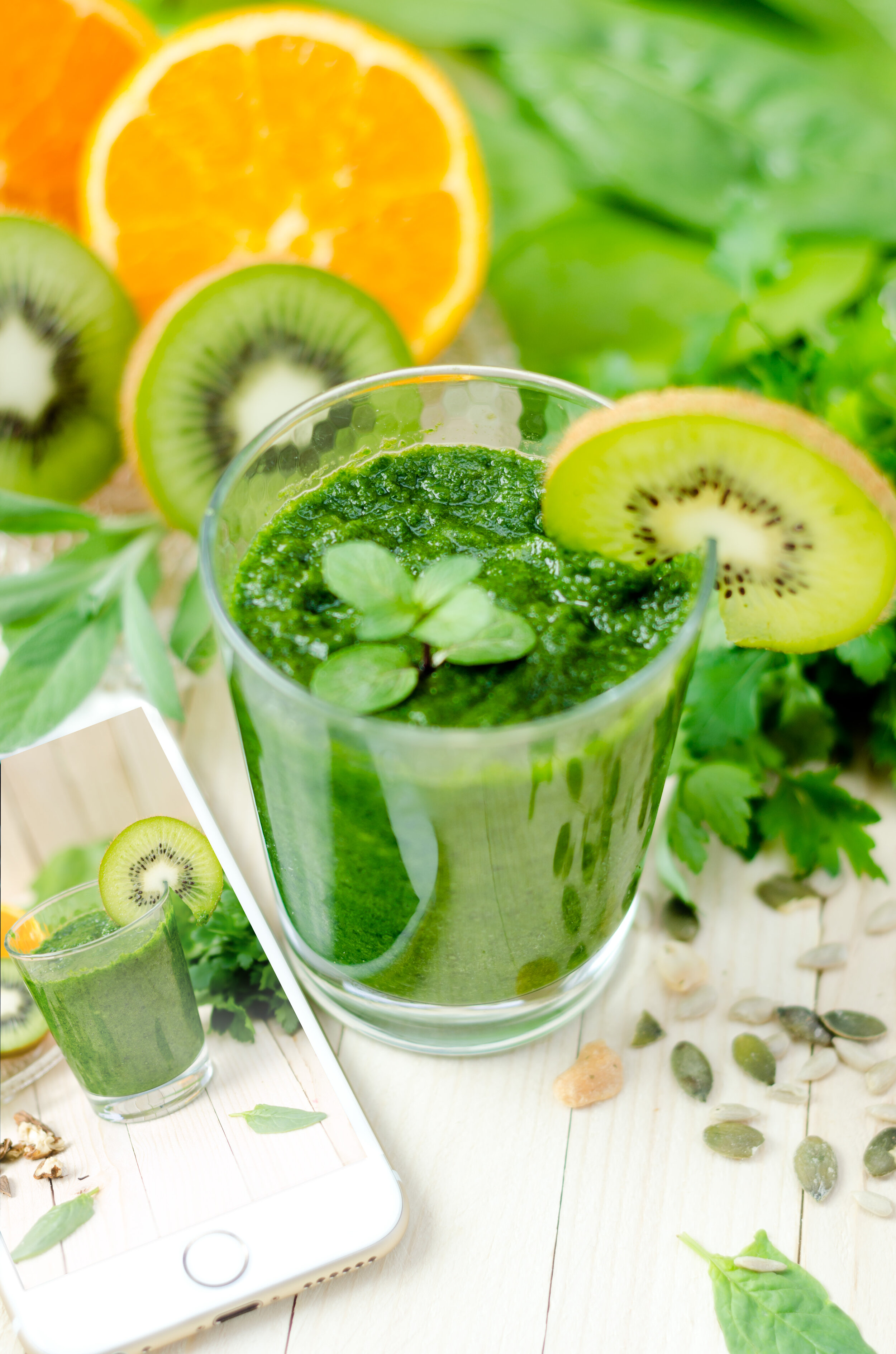 Healthy green smoothie with spinach, kiwi and orange and mobile