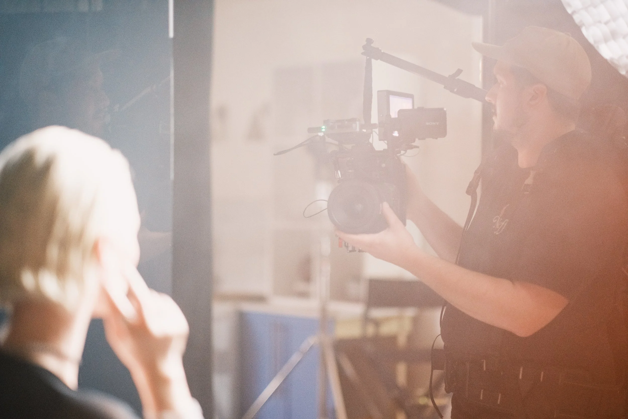 Filmmaker filming a woman in a studio with professional video equipment and lighting.