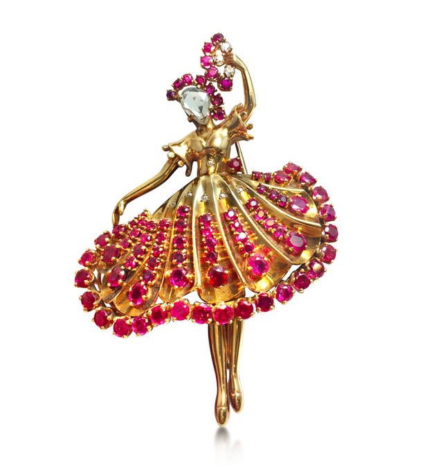 A ruby and diamond ballerina brooch, attributed to John Rubel. Designed as a dancer set with an inverted rose-cut diamond face, holding the a fan set with rubies and diamonds, mounted in gold, circa 1945, 7.0 cm.