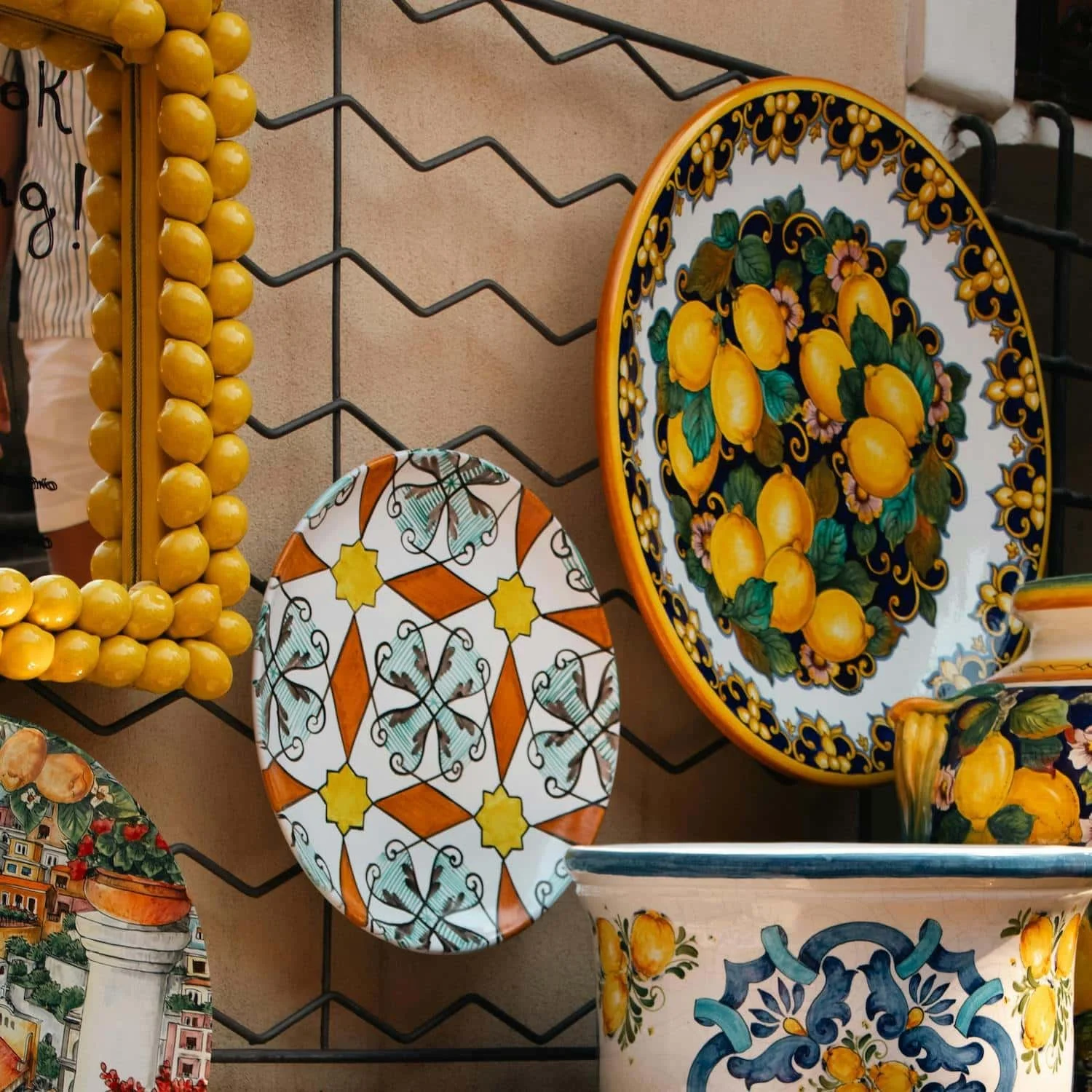 Colorful ceramic plates decorated with bright yellow lemons and traditional Italian patterns displayed at a shop. Shopping for handmade ceramics is one of the popular Amalfi Coast things to do.