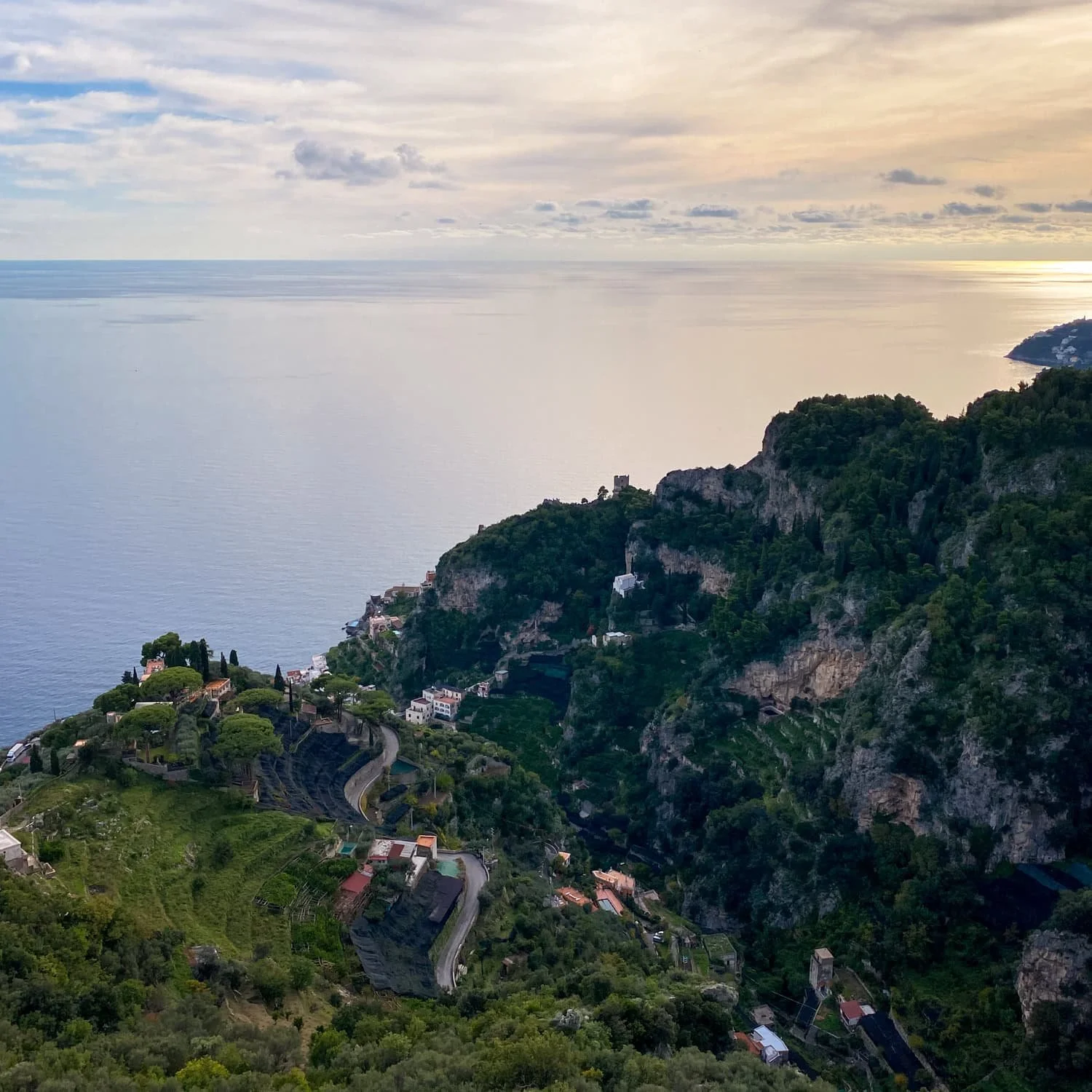 Sunset view over the Amalfi Coast with winding roads, terraced hillsides, and cliffs overlooking the calm sea. Watching golden hour from viewpoints like this is one of the peaceful Amalfi Coast things to do.