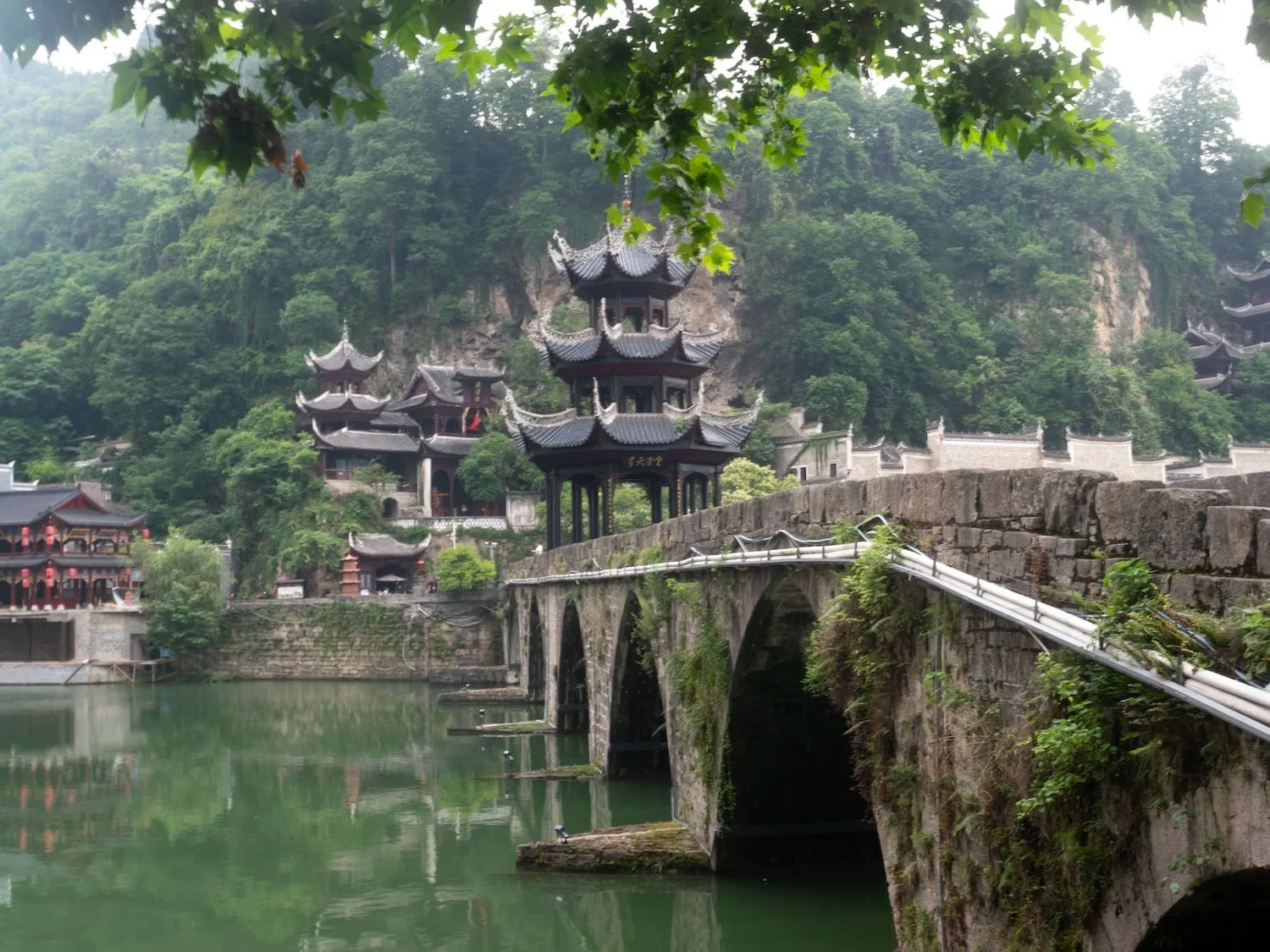 A brightly lit staircase leads toward a natural rock arch framed by towering cliffs at night. Navigating major attractions and crowded destinations can be a drawback of a group tour China experience.