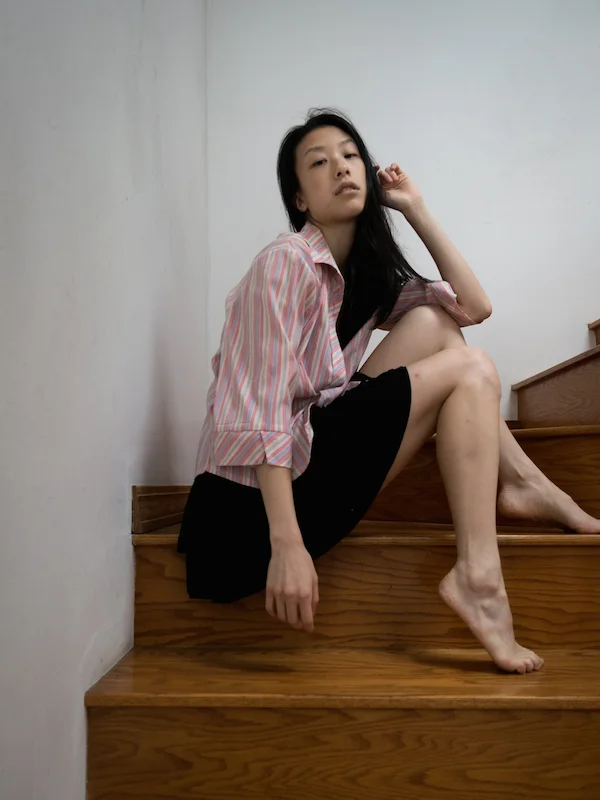 Female east asian style blogger wearing striped pink button-down shirt with black skirt