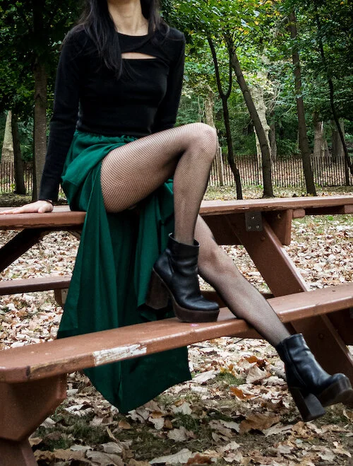 Detail shot of green slit skirt, fishnet tights, black platform boots