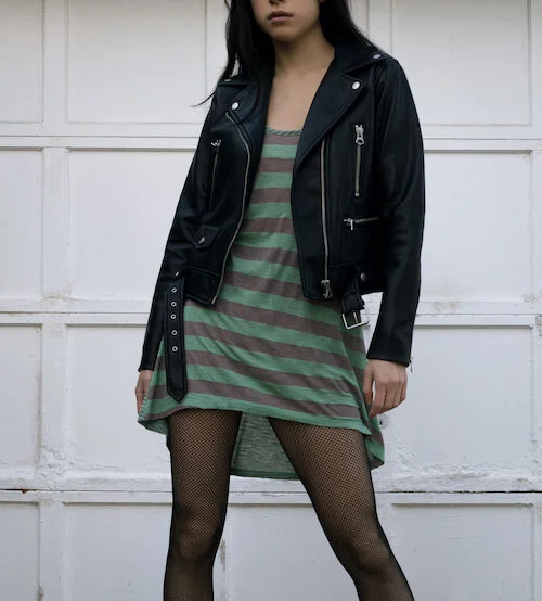 Detail shot of thrifted leather jacket and striped summer dress