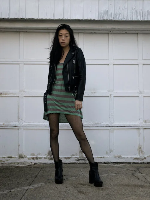 leather jacket, green striped dress, fishnet tights, platform bootss
