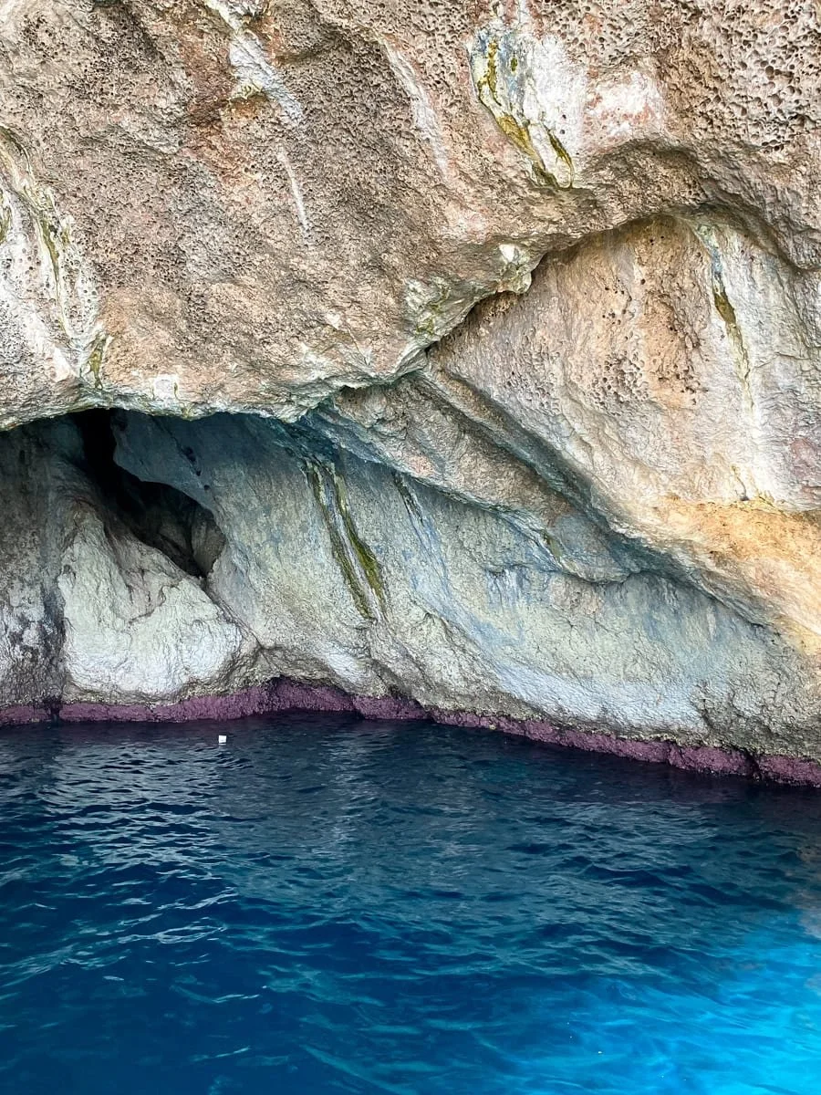  Vertical shot of the Blue Grotto, highlighting the shimmering blue water and the textured stone walls of the sea cave 
