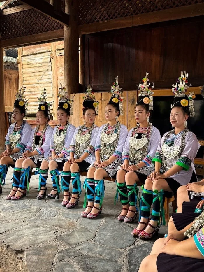Women wearing traditional ethnic dress and silver jewelry during a cultural performance.