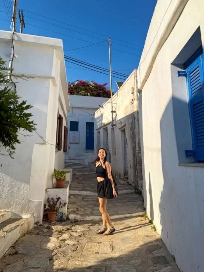  Woman walking through a whitewashed alley on a Greek island. The best eSIM for Greece keeps you connected as you explore. 