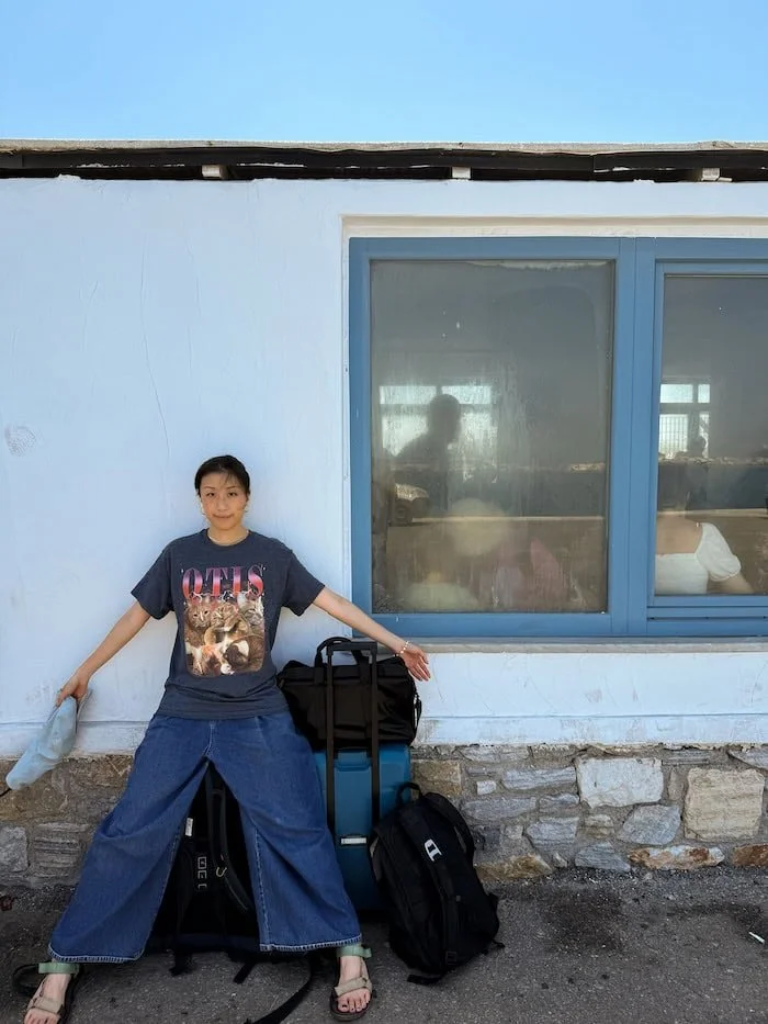  Traveler standing with luggage outside a ferry terminal in Greece. The best eSIM for Greece helps you stay connected from arrival. 