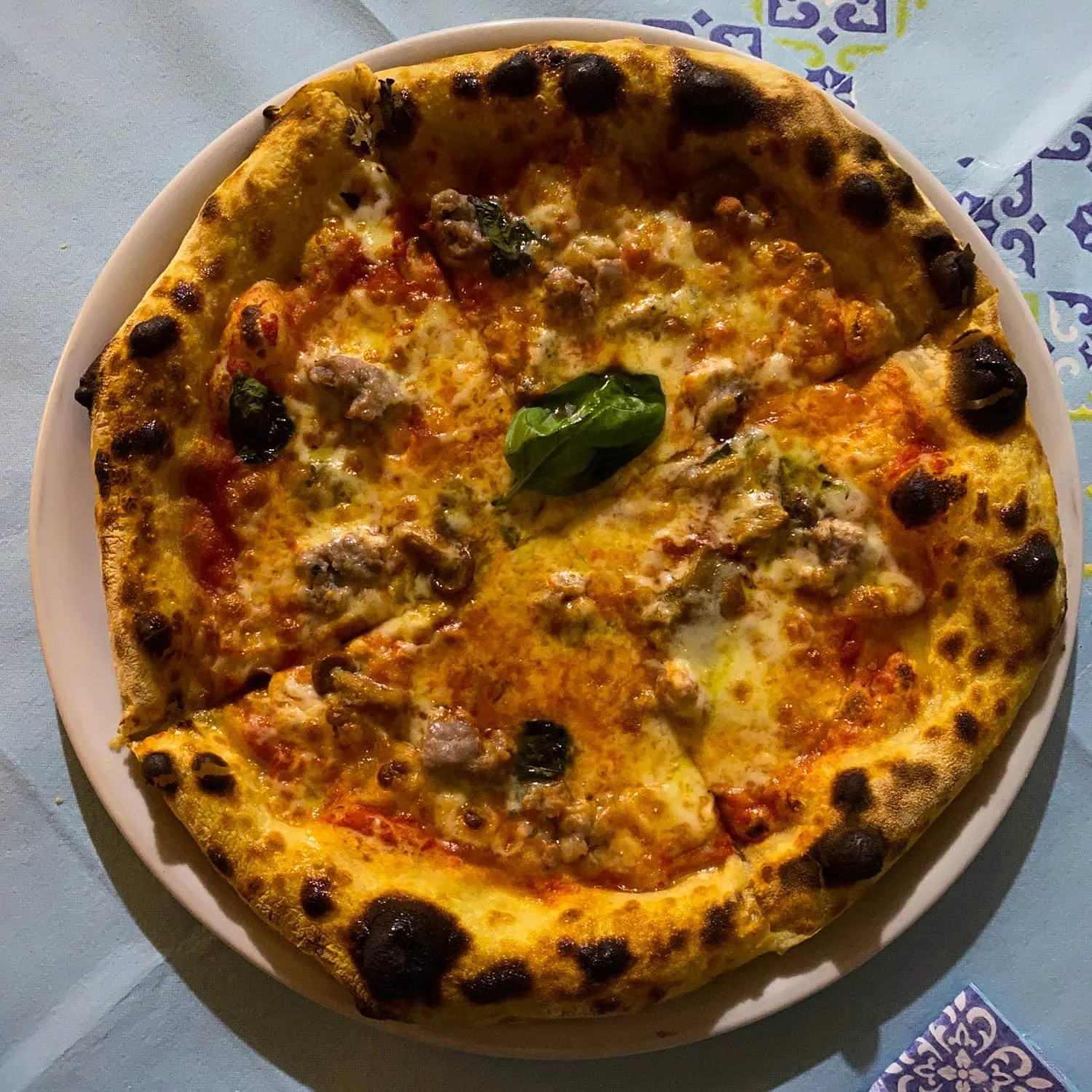 Neapolitan style pizza with blistered crust topped with melted cheese, tomato sauce, mushroom, and fresh basil. Trying authentic pizza near the Amalfi Coast is one of the must try food experiences.