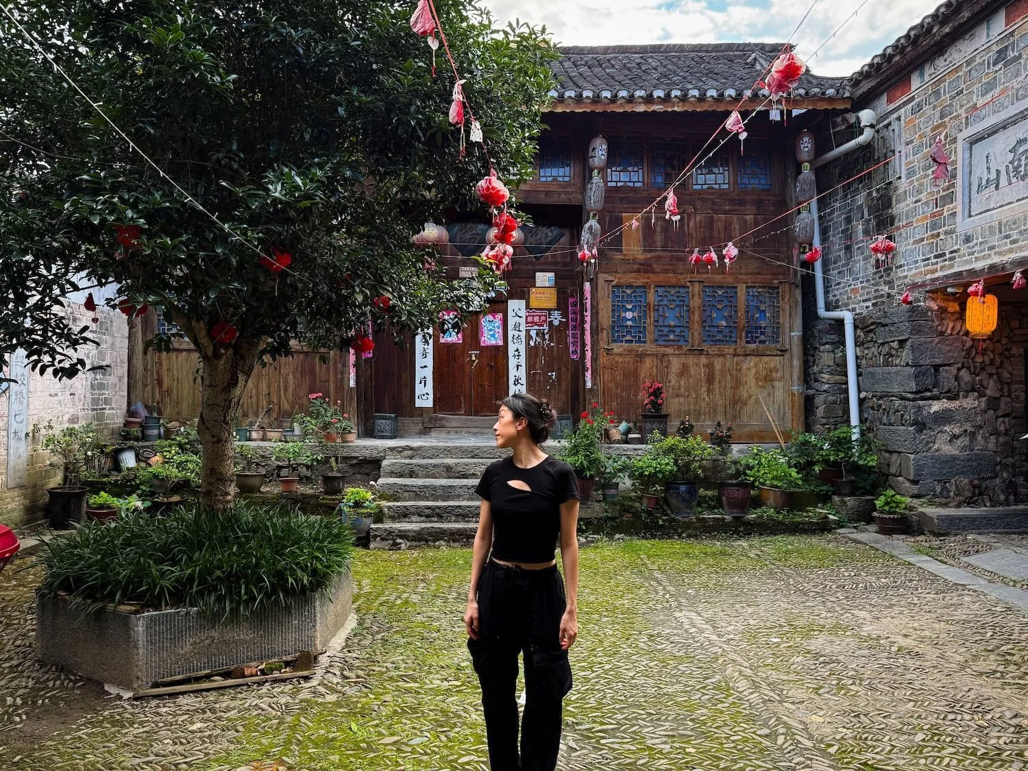 Traveler standing in a traditional courtyard in a Dong village in Guizhou, China. This 2 week China itinerary includes unique cultural destinations like this.