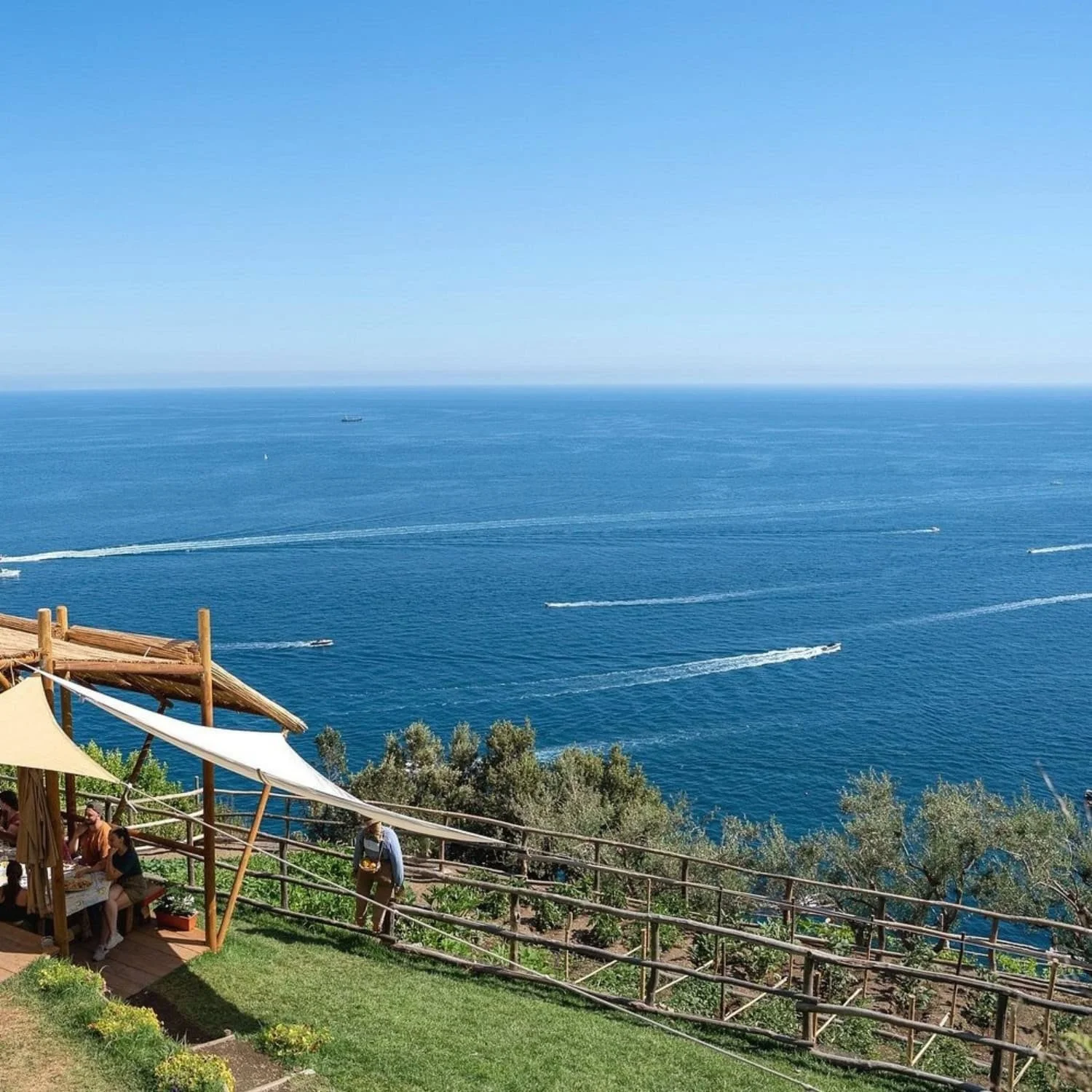 Outdoor terrace restaurant overlooking the deep blue sea with boats leaving white trails across the water along the Amalfi Coast. Enjoying meals with views like this is one of the memorable Amalfi Coast things to do.