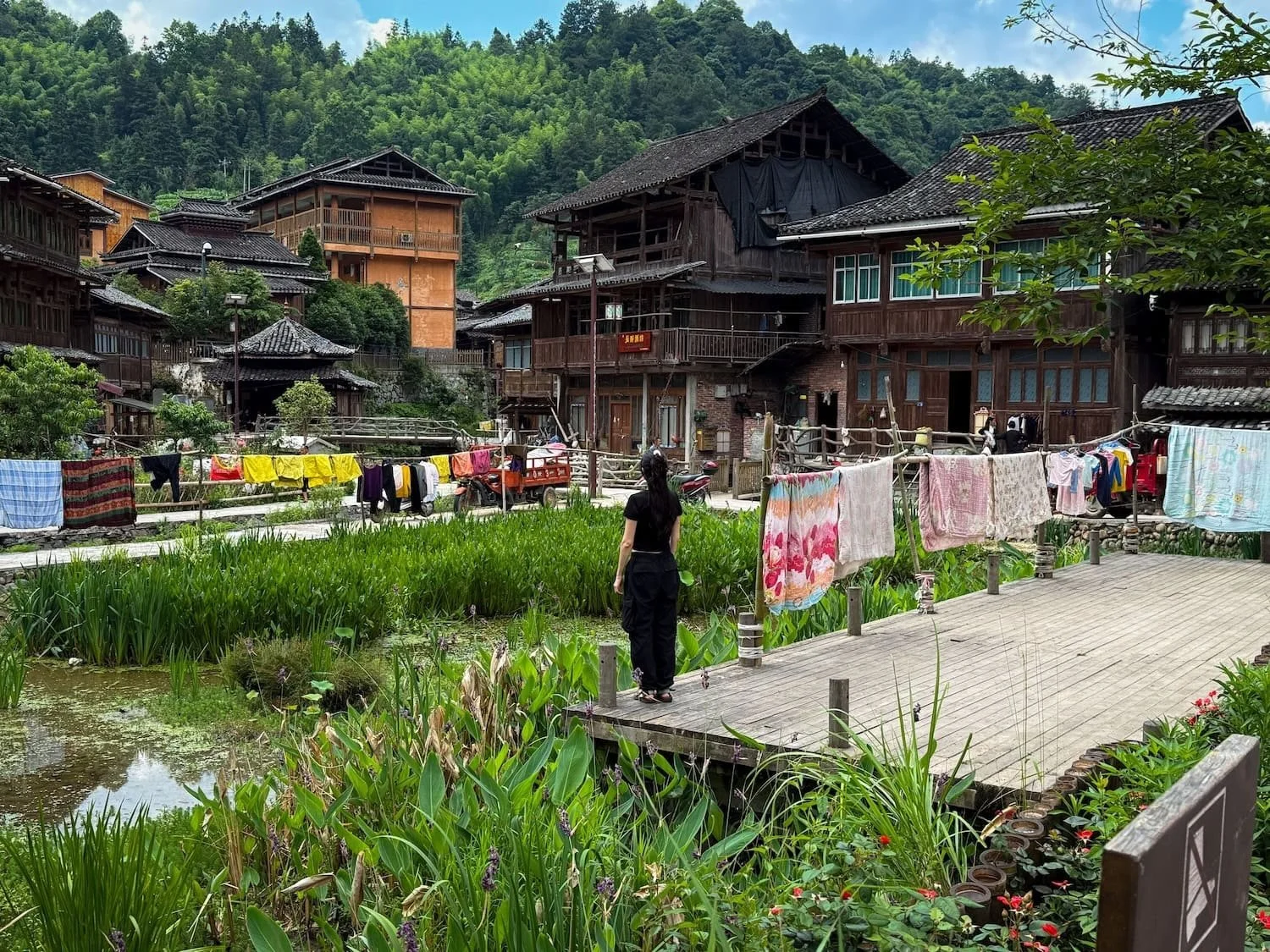 Traveler walking through a peaceful traditional village surrounded by lush mountains. Exploring authentic villages at a relaxed pace is one reason travelers choose Eastogo in China.