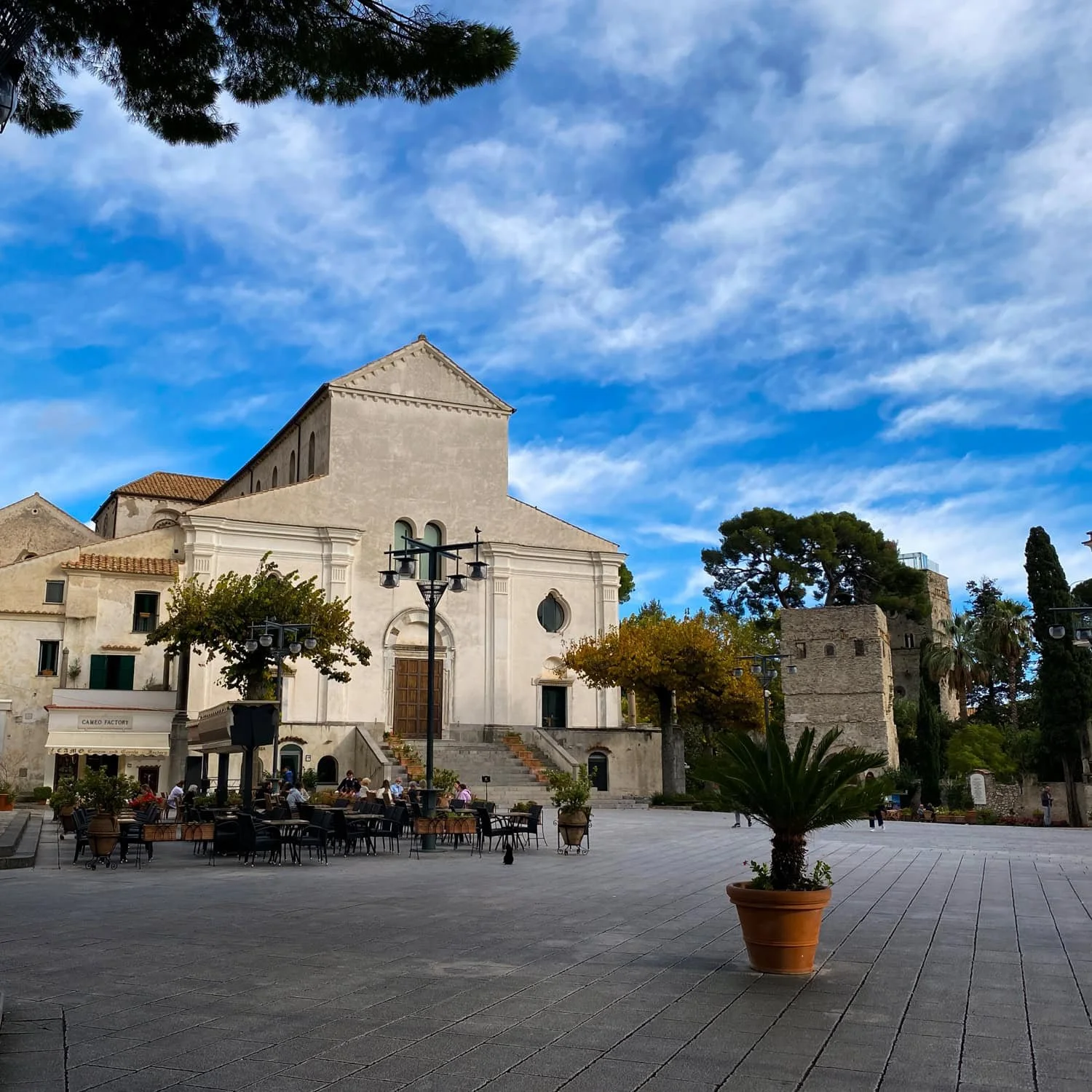 Ravello cathedral and open piazza with outdoor café tables and historic buildings surrounding the square. Visiting quiet hilltop towns like Ravello is one of the relaxing Amalfi Coast things to do.