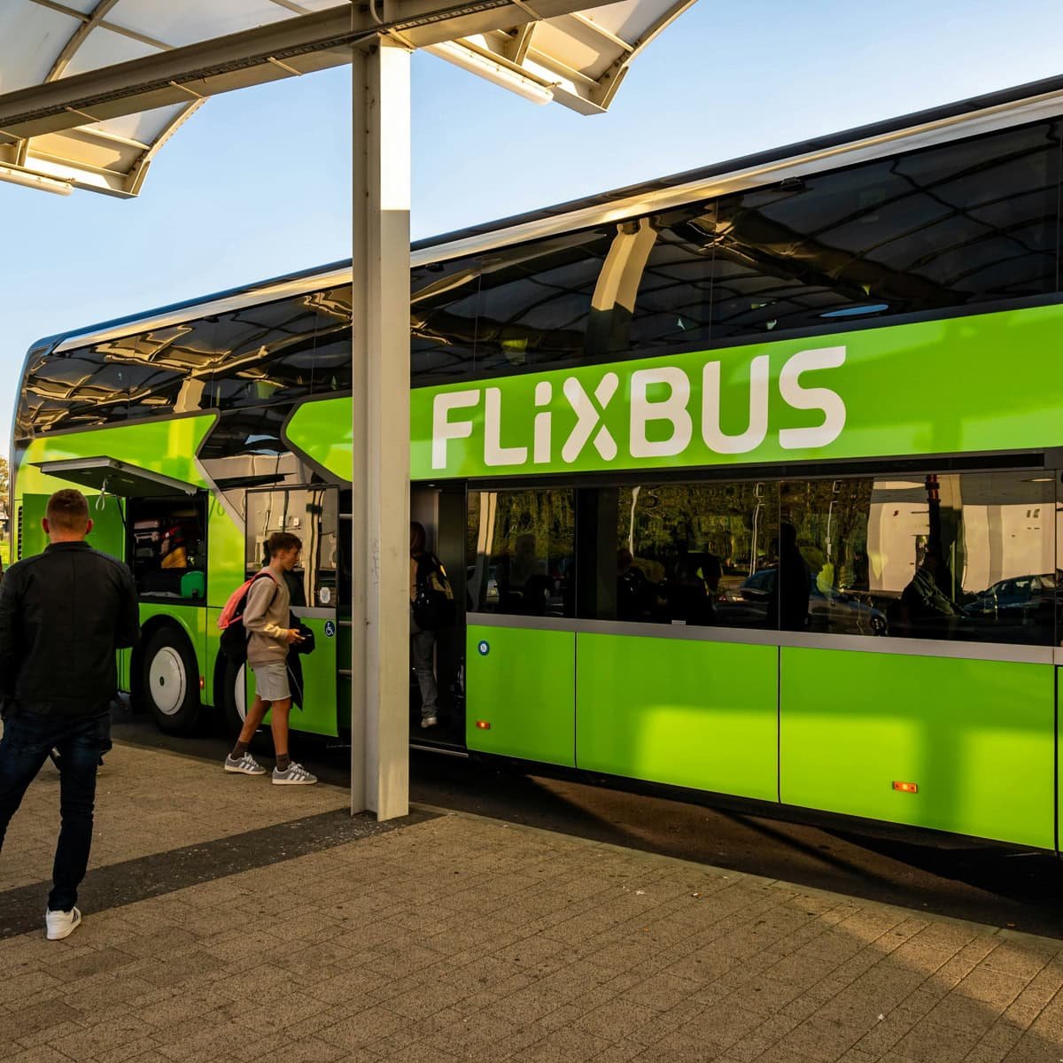 Man wearing beige sweatshirt boarding a green flixbus to get from naples to sorrento.