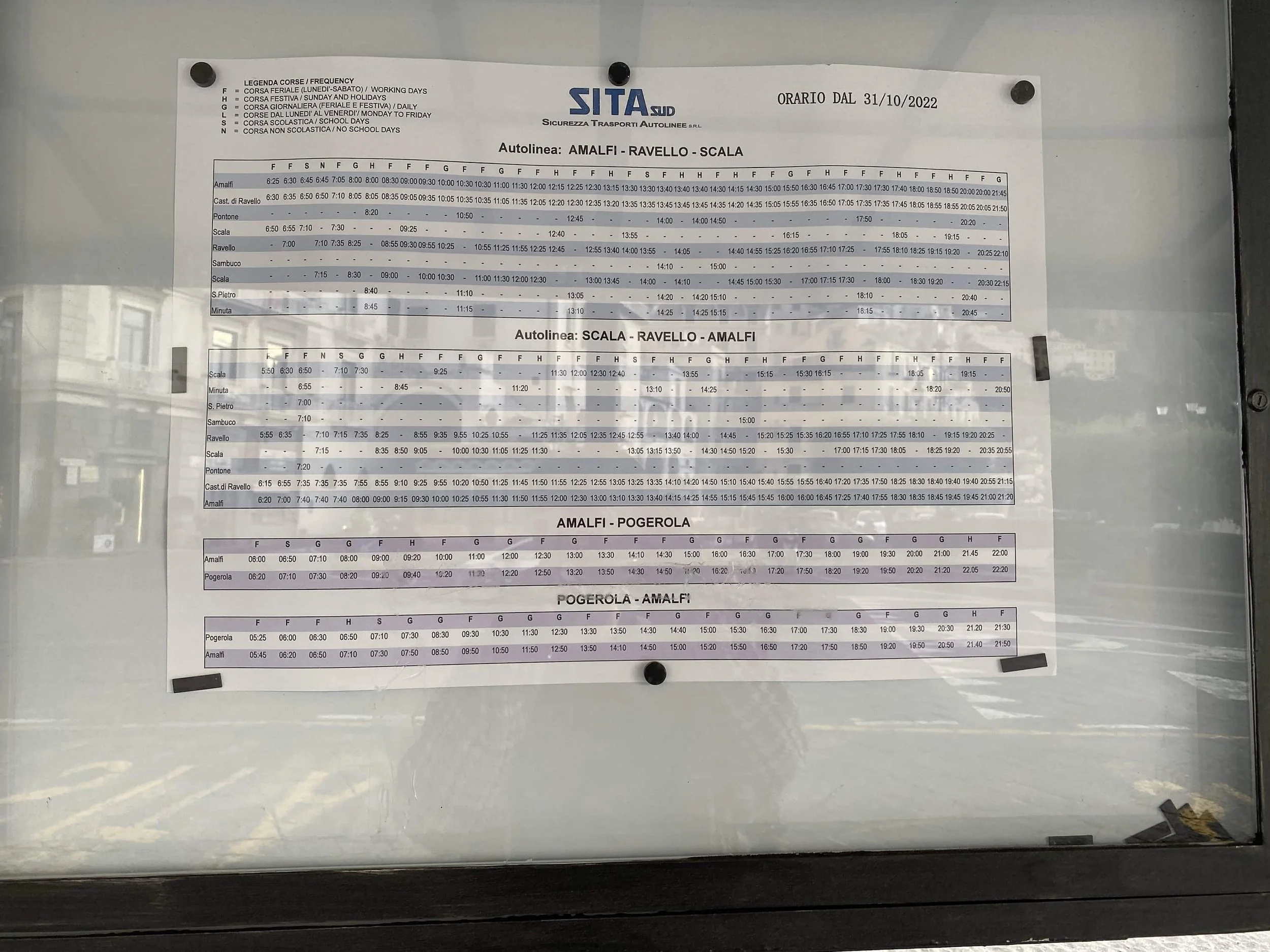 Bus schedule posted at a stop near Caleidoscopio Amalfi bnb showing routes and times between Amalfi, Ravello, and Scala on a printed timetable.
