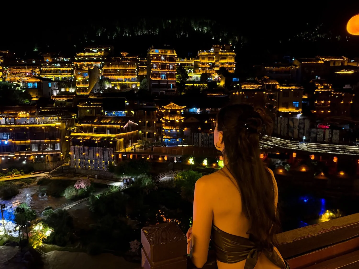 Night view overlooking an illuminated traditional Furong Ancient village in China from a balcony. This scenic stop highlights the unforgettable destinations included on an Eastogo group travel China itinerary.