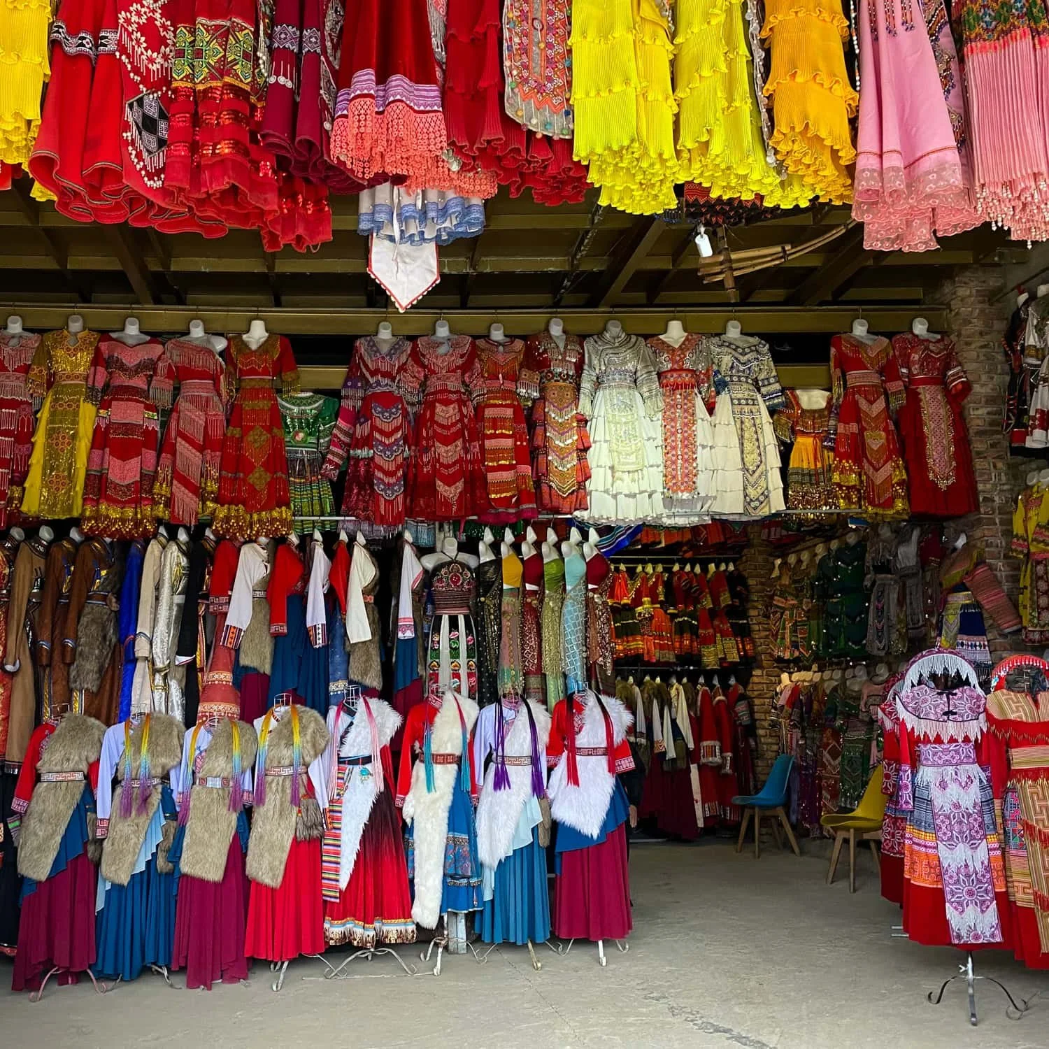 Colorful traditional Hmong and other ethnic garments displayed in a vibrant clothing shop in Sapa, Vietnam. The rich colors and intricate embroidery highlight local culture, offering a glimpse into why Sapa may be worth visiting.