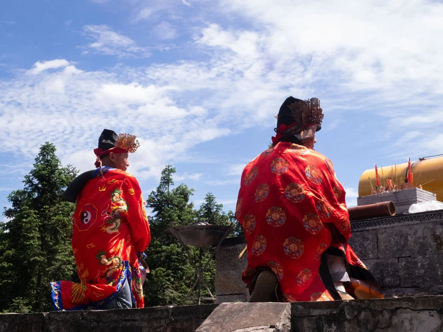 Two people wearing traditional ceremonial robes participate in a cultural event. Local guides on a group tour China can provide valuable context and insight into regional customs and traditions.