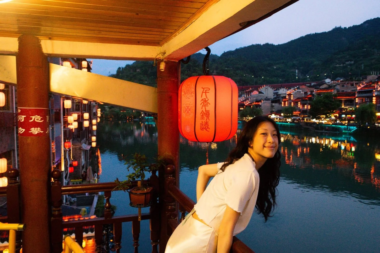 Traveler overlooking Fenghuang Ancient Town at night. This 2 week China itinerary features scenic historic towns across China.