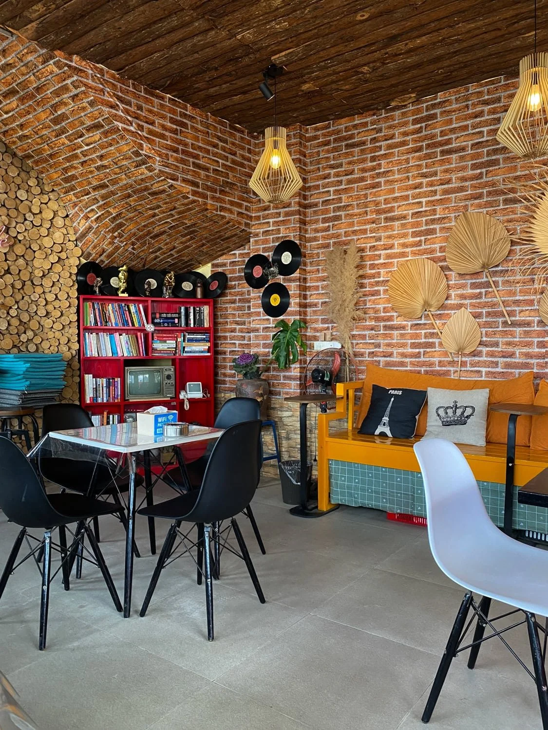 Cozy café interior in Sapa featuring brick walls, vinyl records, modern furniture, and retro decor with Eiffel Tower and crown pillows. Stylish cafés like this blend tradition and trendiness, nudging the answer toward yes for is Sapa worth visiting.