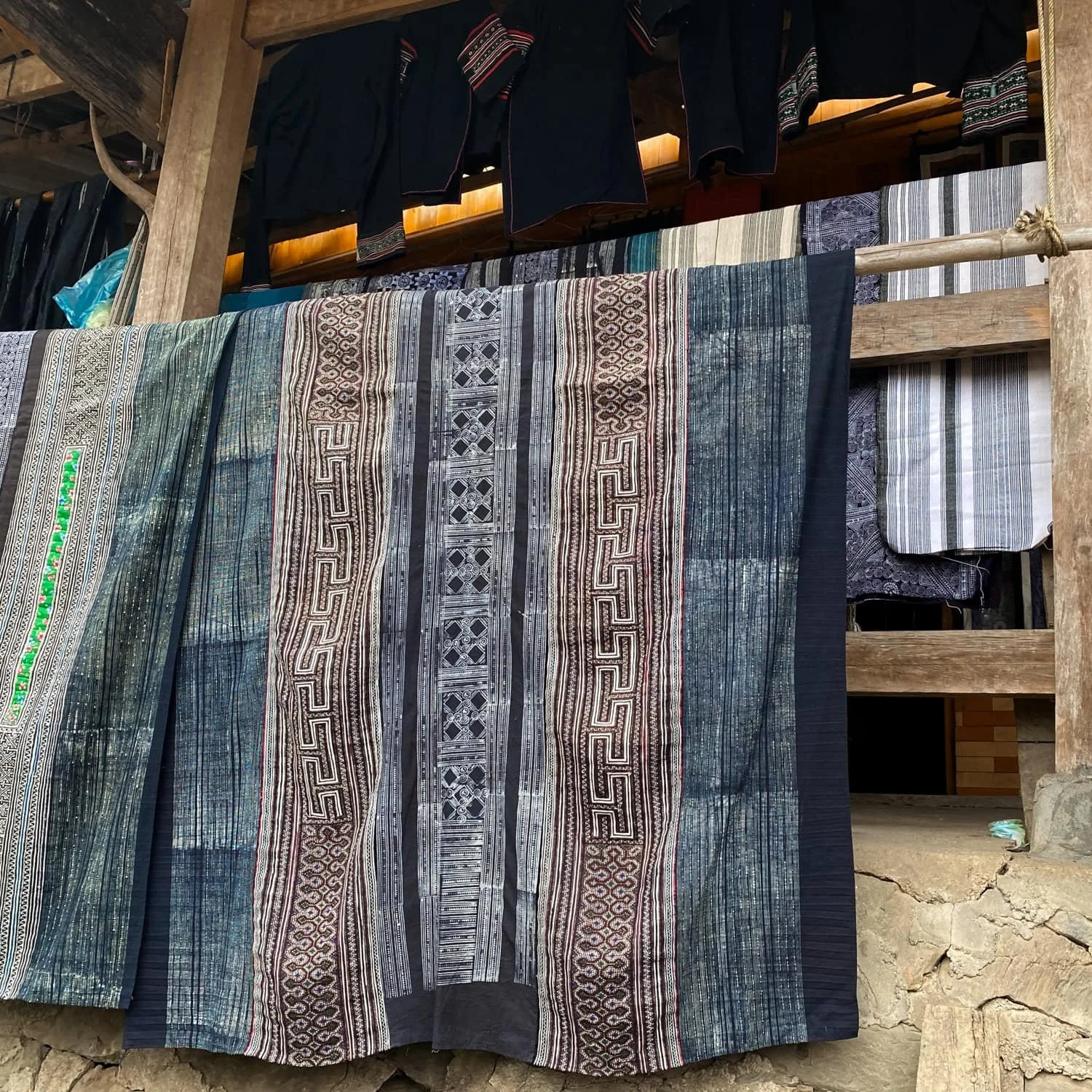 Handwoven indigo-dyed fabric with intricate ethnic patterns hanging outside a wooden home in a Sapa village. This kind of traditional craftsmanship is one reason why travelers say yes when asked is Sapa worth visiting.