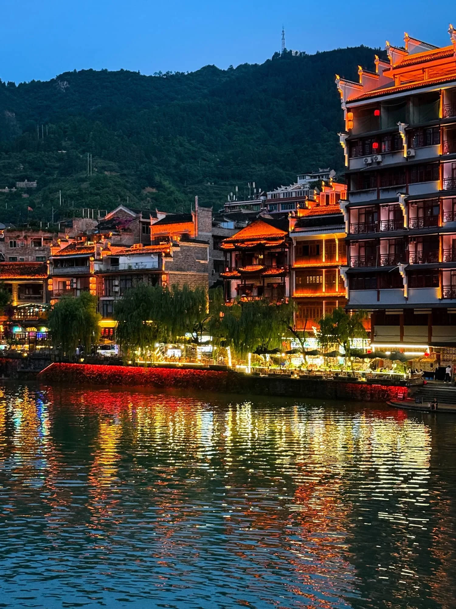Riverside view of Zhenyuan Ancient Town illuminated at night. This 2 week China itinerary includes charming ancient towns.