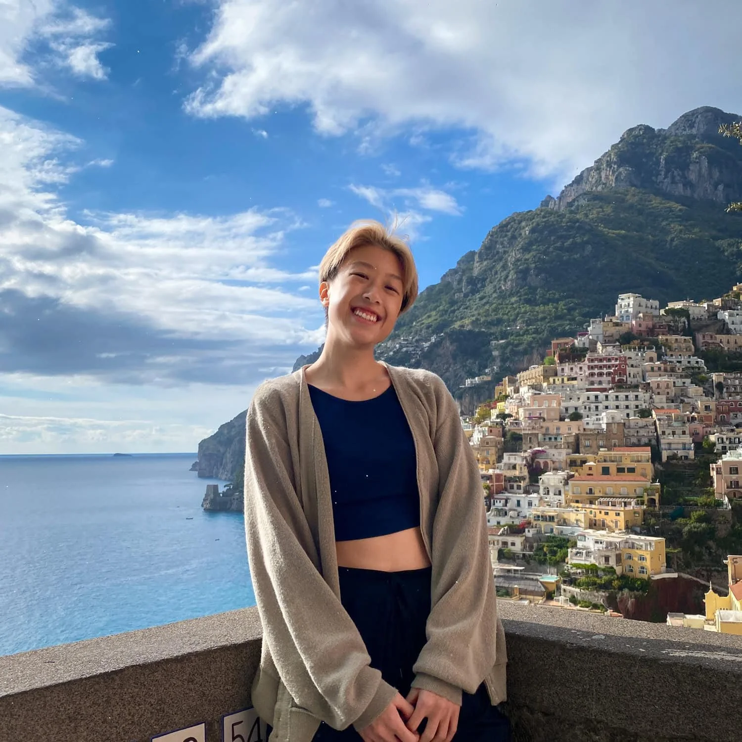 Traveler smiling while standing at a scenic viewpoint overlooking Positano’s colorful cliffside houses and the blue sea on the Amalfi Coast. A popular photo stop and one of the memorable Amalfi Coast things to do.